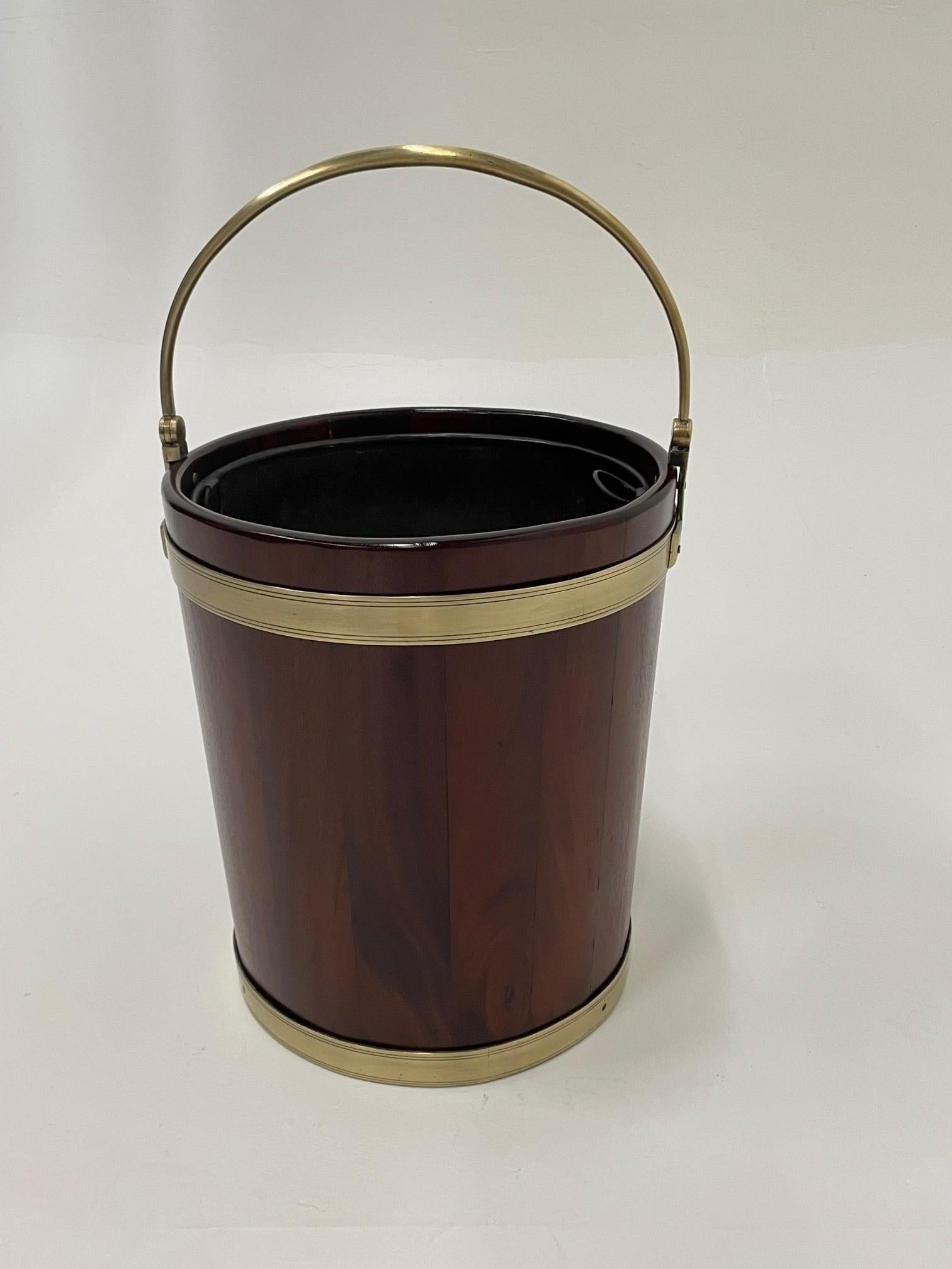 A rare and handsome English antique peat bucket crafted of mahogany and brass with original liner. Measure: 25