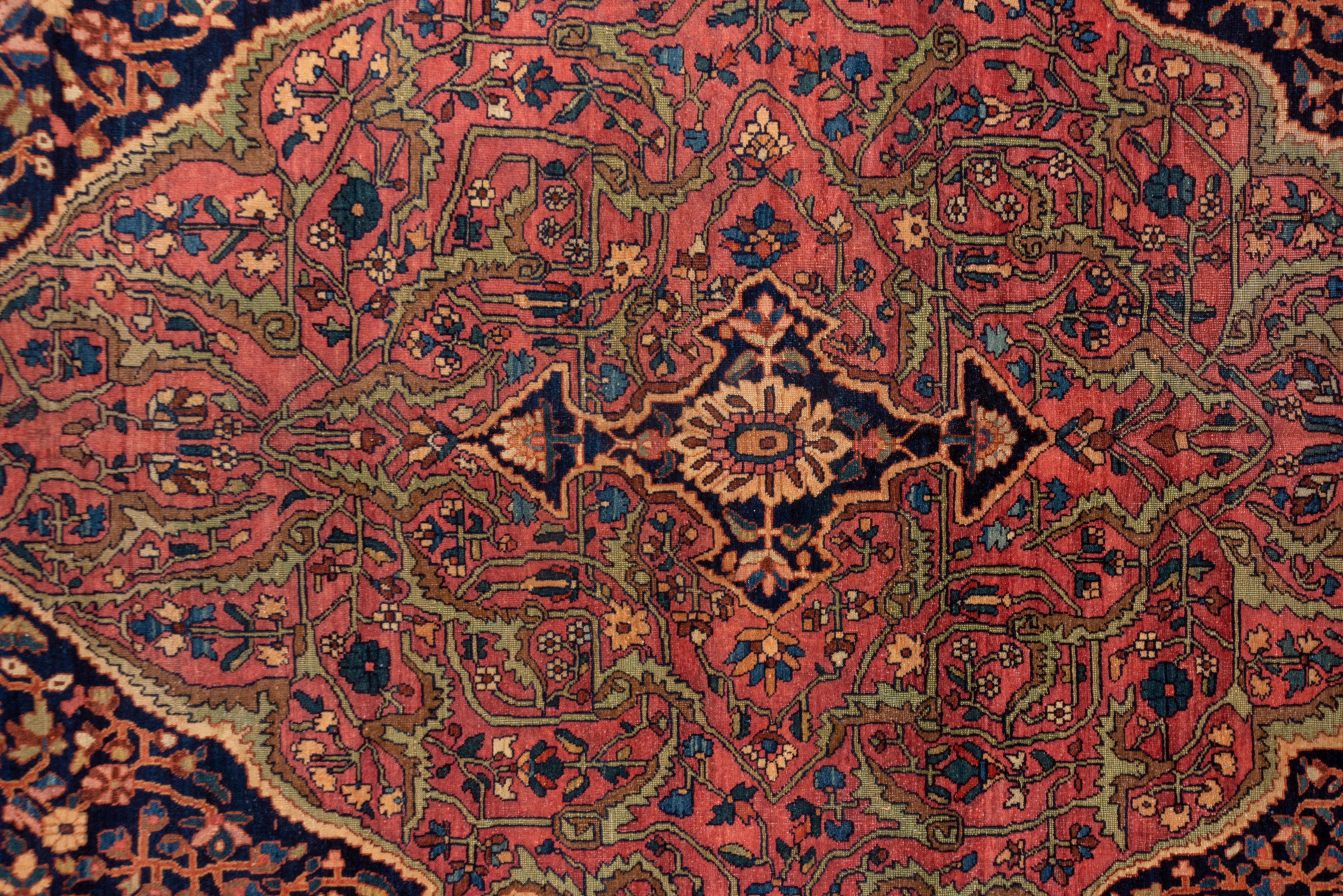 Well-detailed, extended sand corners position the navy millefleurs pattern field and its barbed elliptical rose lozenge medallion with star shaped pendants. This well-executed west Persian village carpet has a rust main border featuring poly-chrome