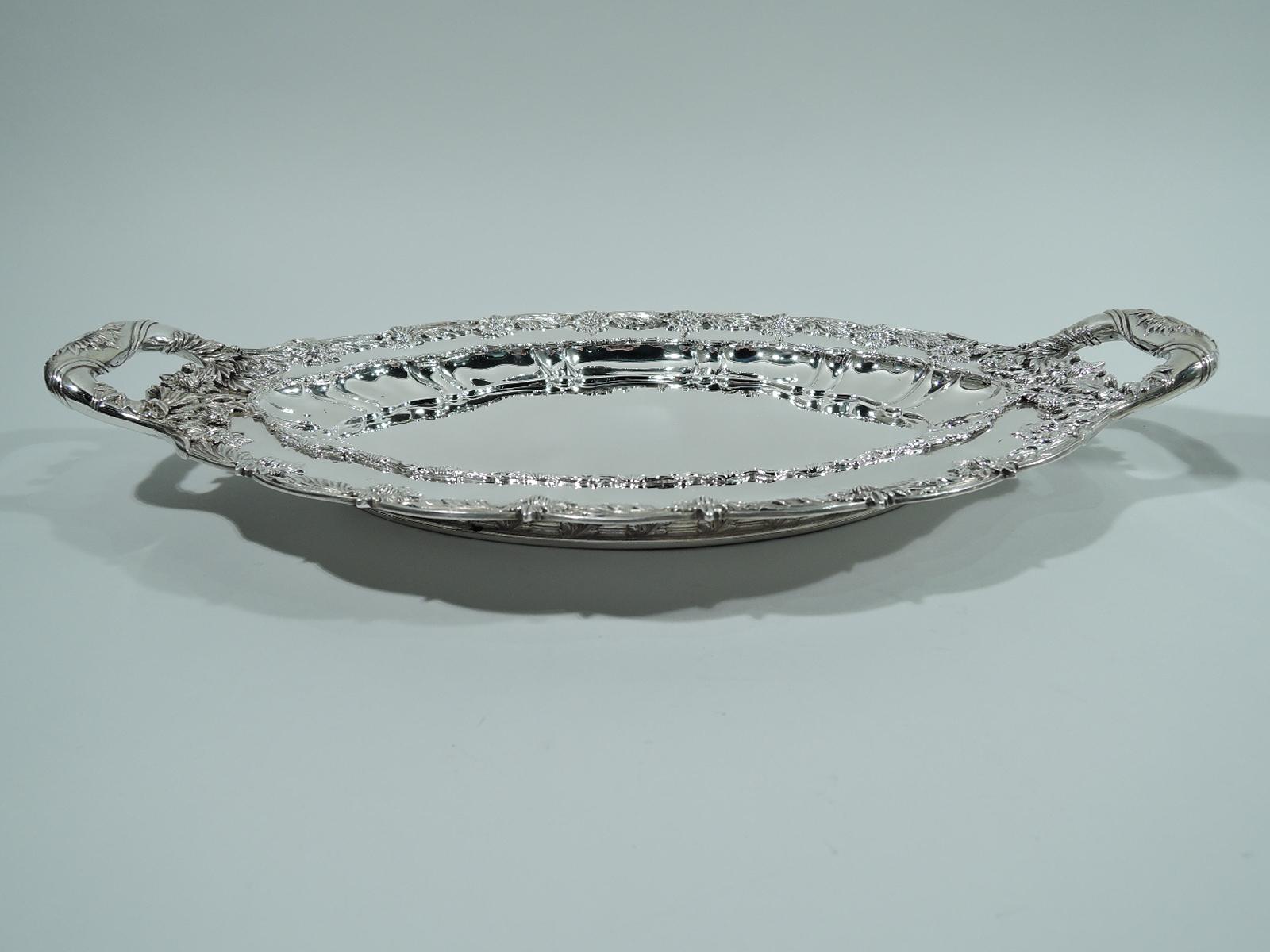 Chrysanthemum sterling silver serving dish. Made by Tiffany & Co. in New York. Ovalish well, curved sides with lobing and applied leaf border, and scalloped rim with the famous chrysanthemum flower heads alternating with leaves. A profusion of