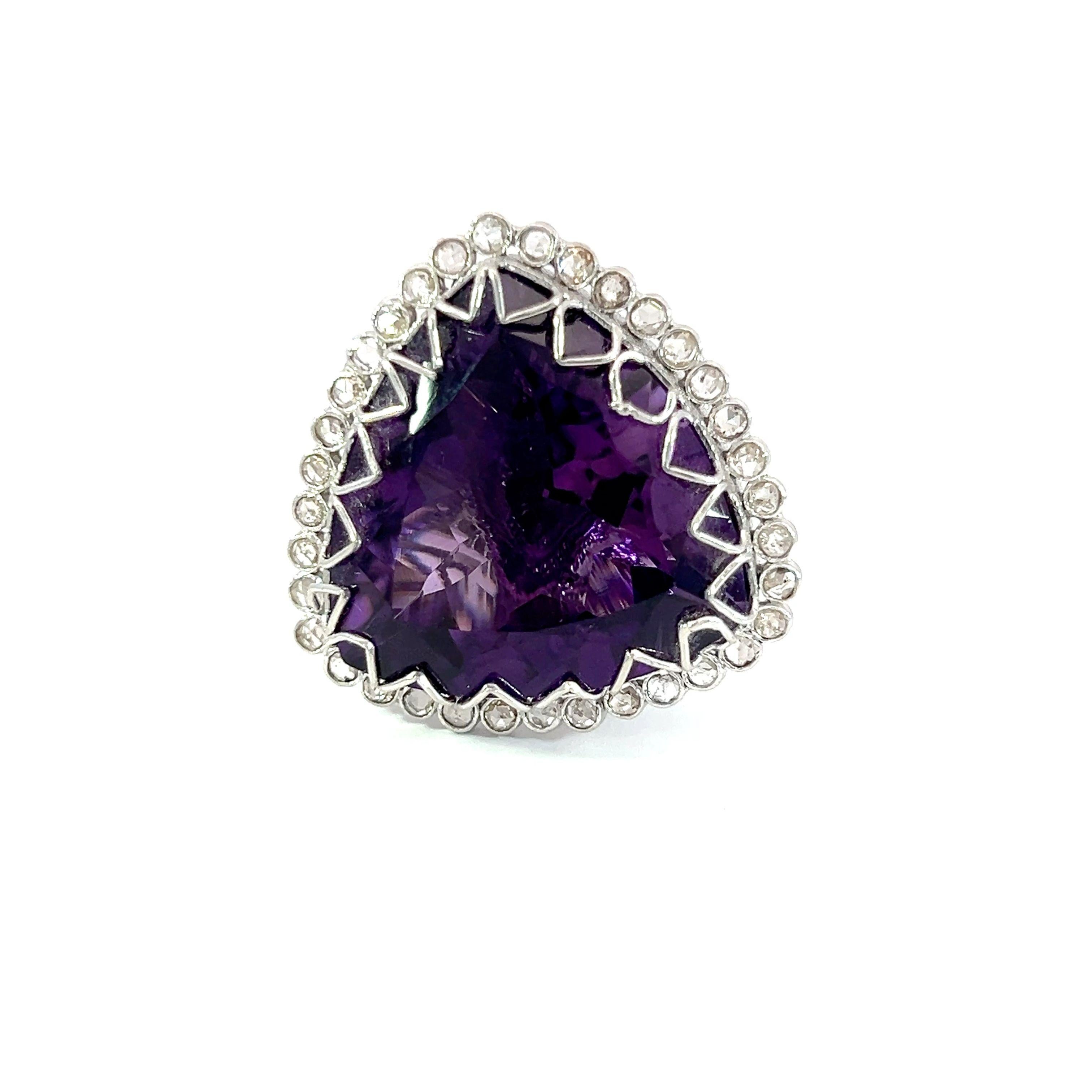 Este exquisito anillo presenta una impresionante gema Amatista de 28 quilates, elegantemente enmarcada por una serie de brillantes diamantes de 0,60 quilates. Su intrincado diseño y vibrante color lo convierten en una pieza perfecta para cualquier