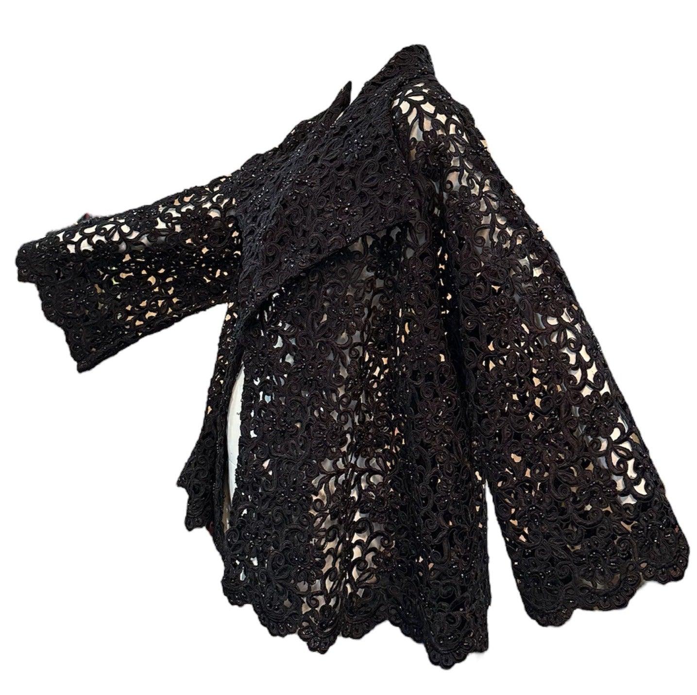 This exquisite evening jacket features delicate beadwork on an unlabeled, midnight black cutwork lace fabric. The A-line silhouette, flared sleeves, and oversized shawl collar add a touch of elegance. Open front. Sheer and unlined, this jacket is