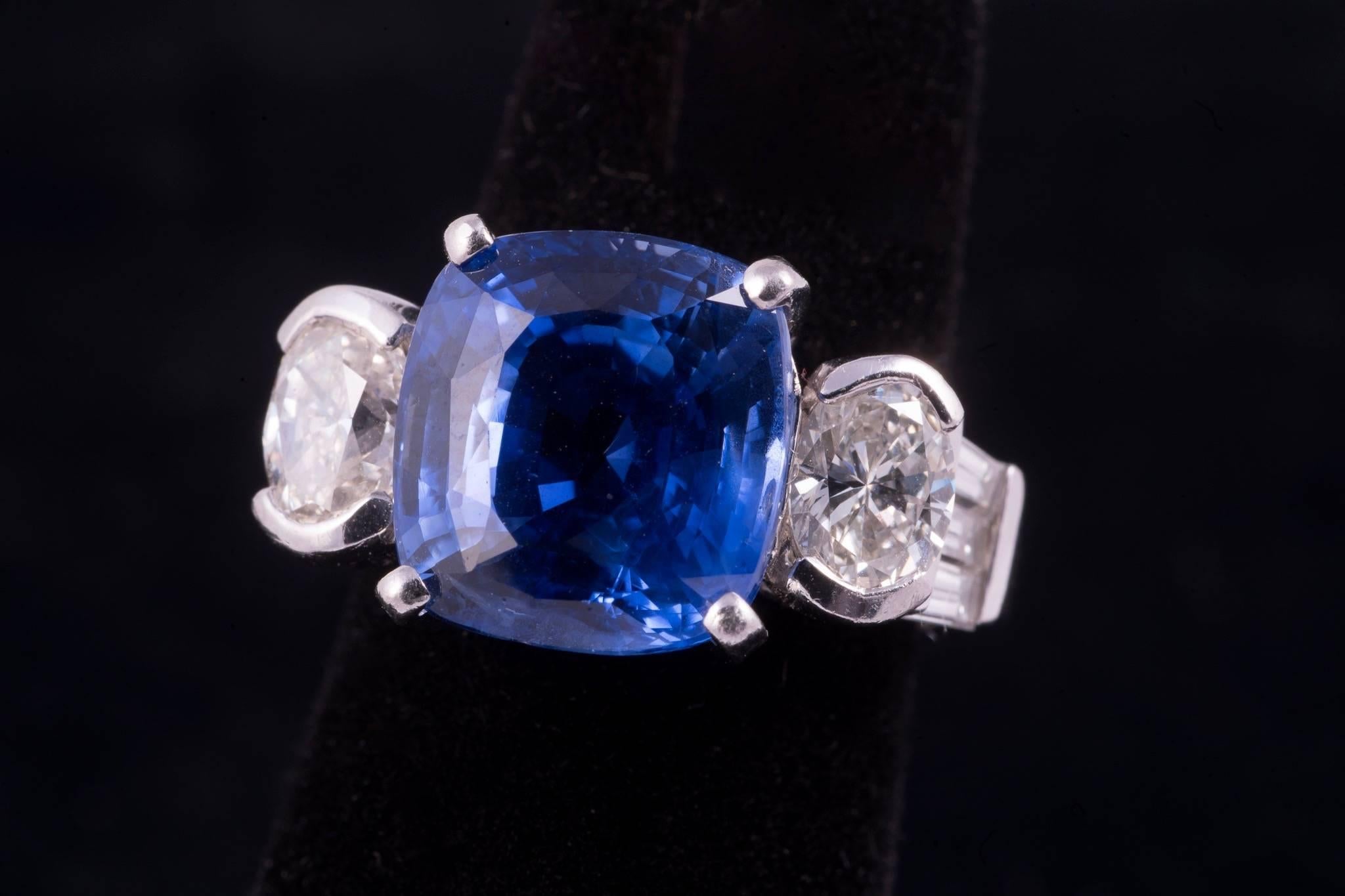 Sapphire and diamond ring. The center sapphire is is cushion cut, weighs approx. 8.75cts, has strong medium blue color and clean clarity. There are 2 oval diamonds on either side that weigh approx. 1.25cts total. There are 6 taper baguette diamonds