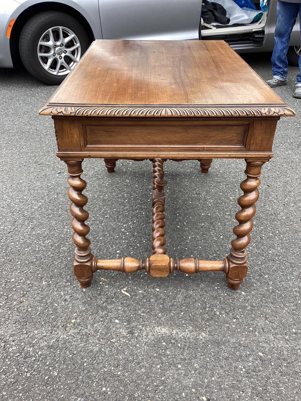 Gorgeous antique French desk with lovely patina and and solid walnut top over handsome barley twist legs. There are 2 front drawers for storage and a cross-stretcher for stability. The delicate carvings on the drawer fronts and carved accents along