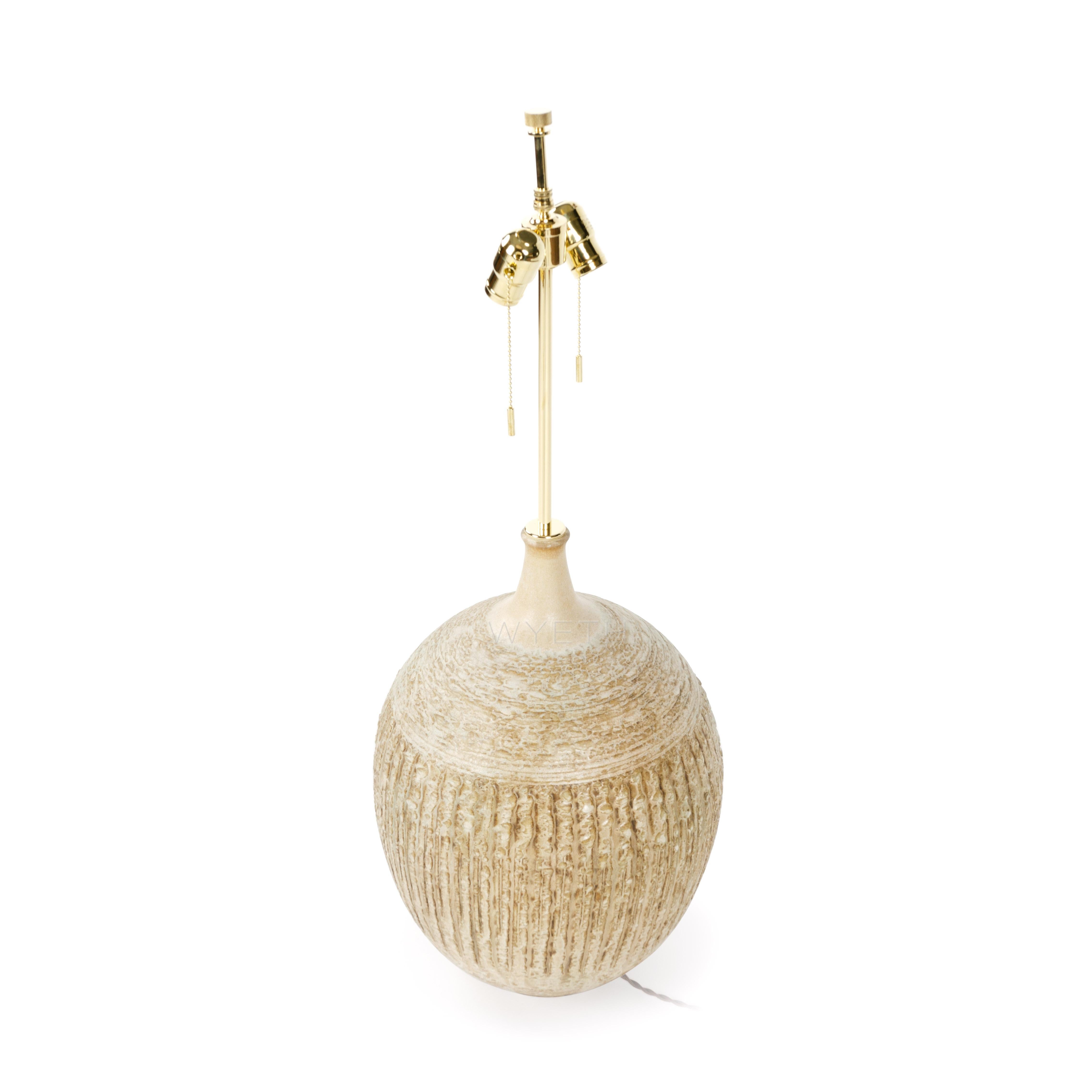 A hand-thrown bulbous sculpted ceramic lamp in a semi lustrous ochre glaze.
Marked with the Design Technics Cypher.