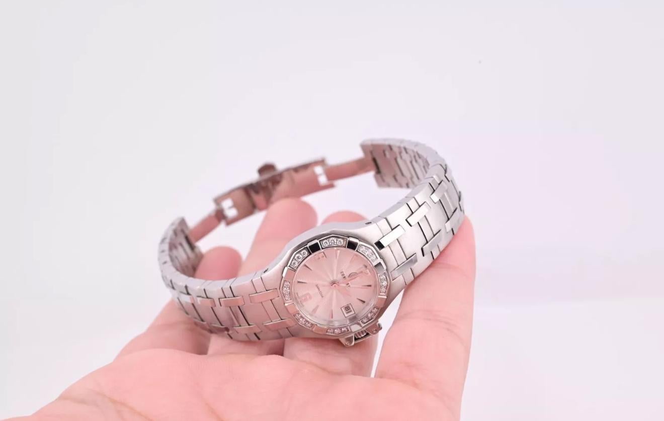 Il s'agit d'une montre Concord Saratoga méticuleusement fabriquée. Le garde-temps est doté d'un bracelet en acier inoxydable avec une finition polie. Le cadran rond, de couleur argentée, est orné de chiffres noirs audacieux à 12, 3, 6 et 9 heures.