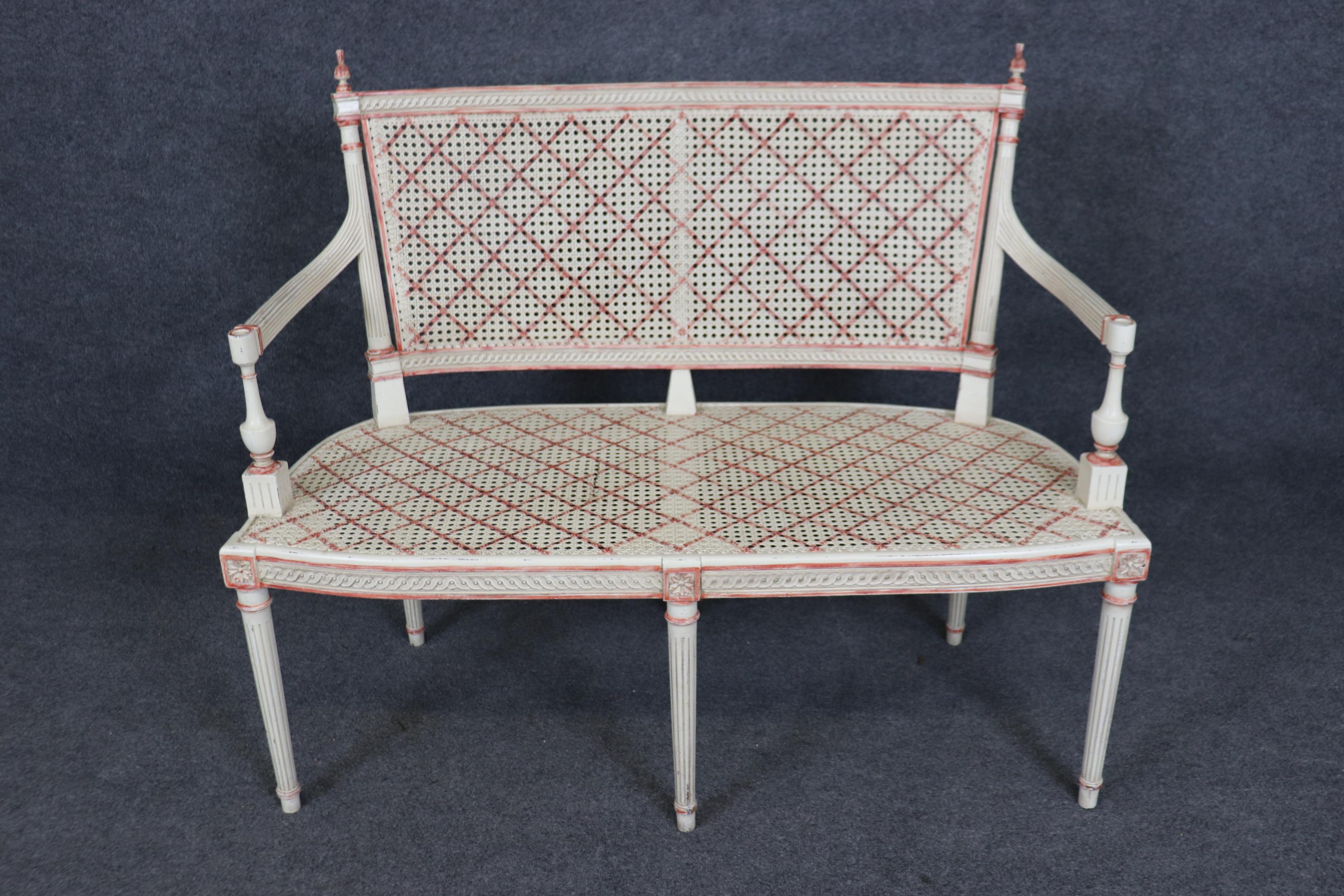 This is a gorgeous painted settee with cross hatched red glazed decoration and a green upholstered removable cushion. The cane is in good condition as is the rest of the frame. The settee has normal age-appropriate signs of wear and signs of use.