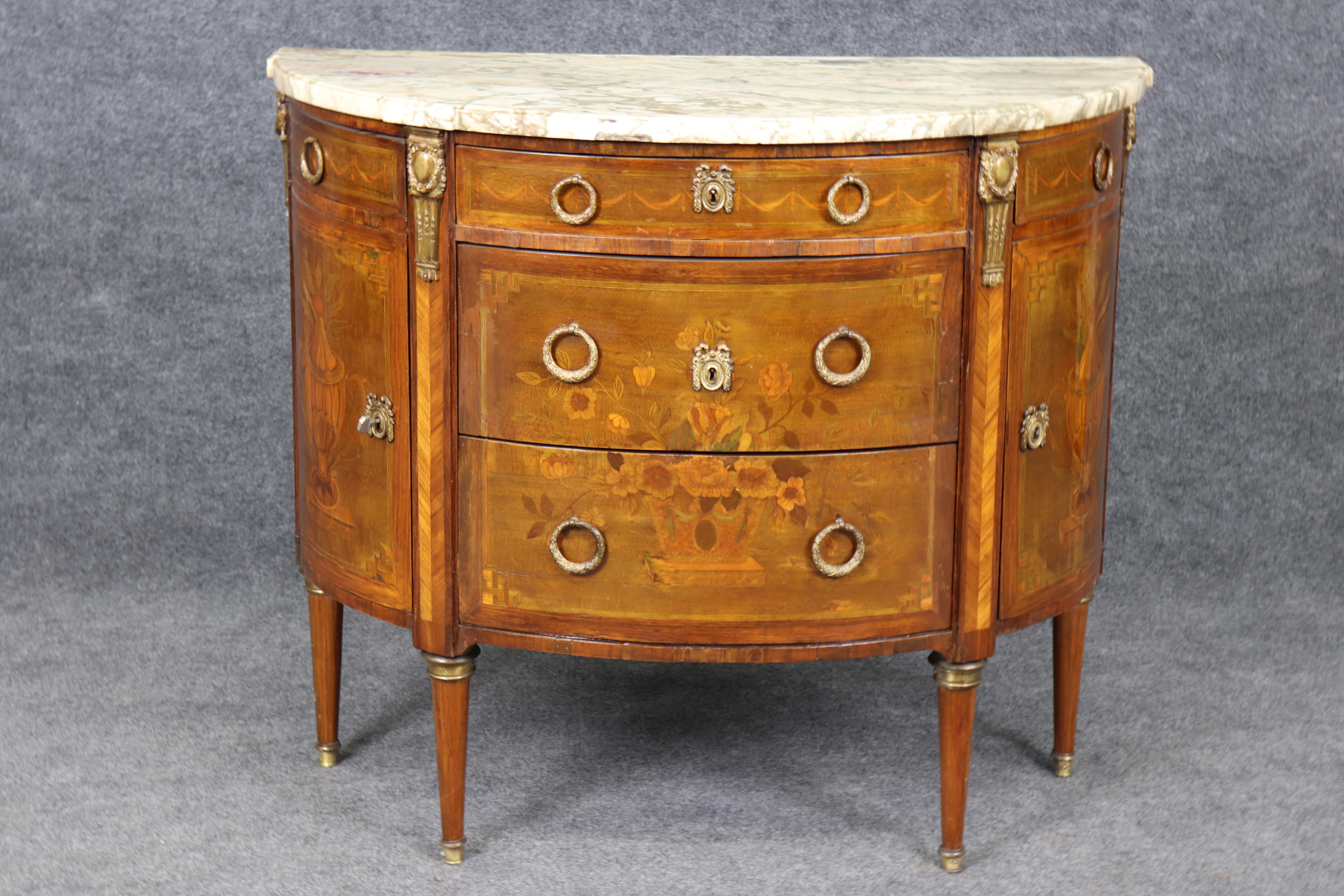 Si tratta di una bellissima commode francese Luigi XV in forma di demilune con splendidi intarsi di fiori e bronzo ormolu. Il pezzo ha un carattere meraviglioso e segni di età e patina. I pezzi risalgono all'epoca del 1880 e sono a coda di rondine.