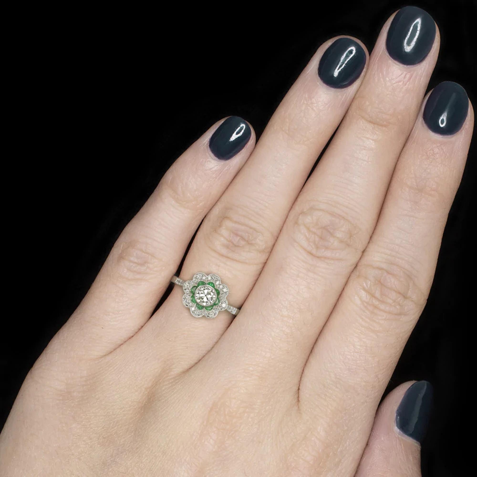 gorgeous diamond and emerald halo engagement ring was inspired by the 1900s and is full of vintage charm! The half carat Old European cut diamond center stone is mounted in a bezel setting with exquisite hand-cut milgrain detail. Cut by hand a