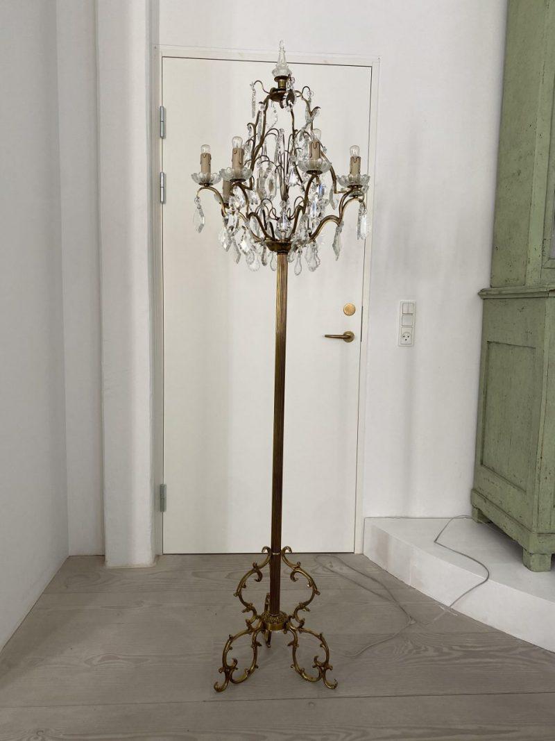 Made of quality brass on an elegant tripod base, with fine rocaille-inspired ornamentation and a fluted rod. The lamp has beautifully decorated clear leaf and drop-shaped prisms and is equipped with 8 arms/lights for electricity with fine petal