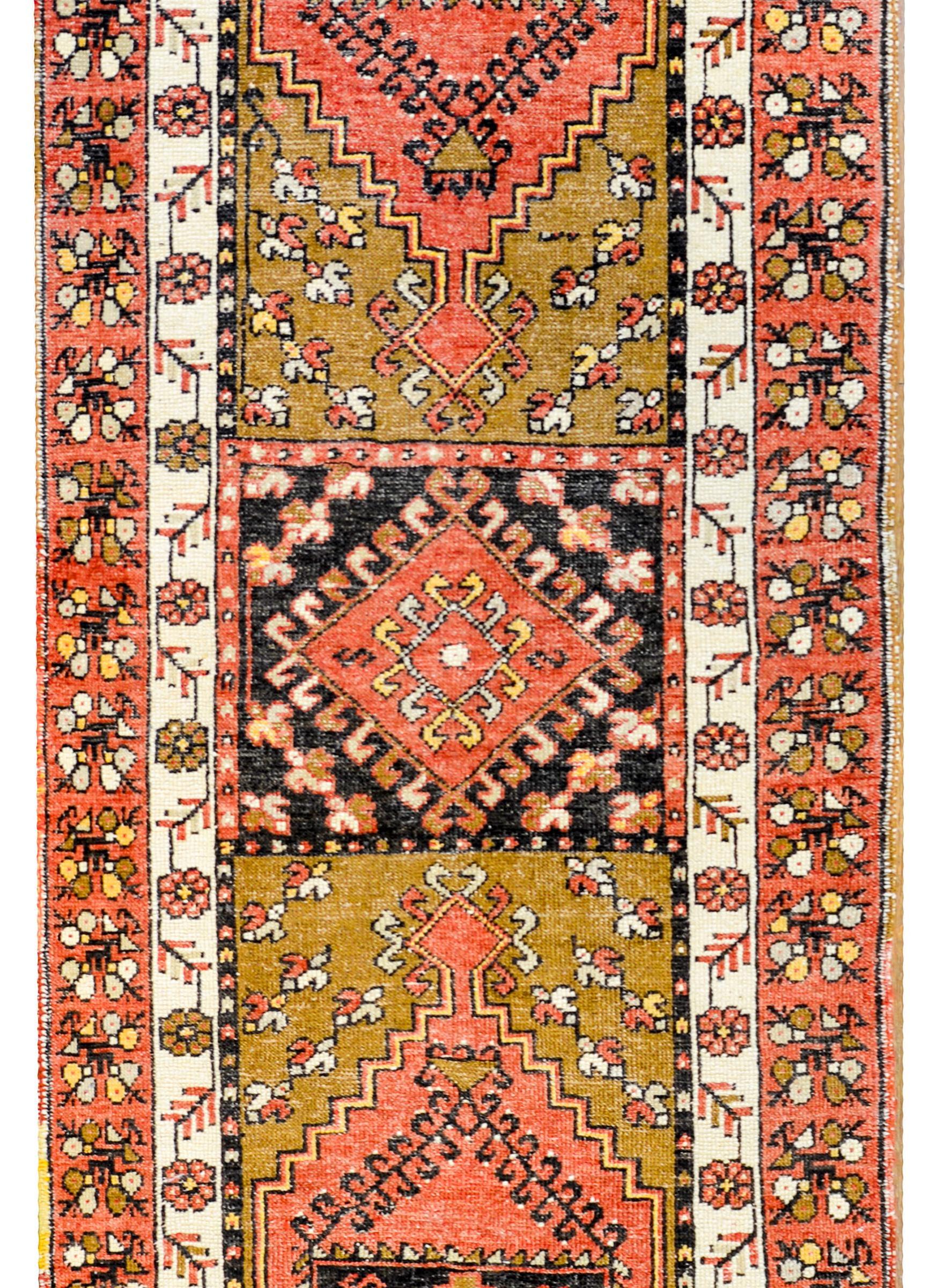 A gorgeous early 20th century Perisan Karajeh Heriz runner with a wonderful tribal pattern containing three large diamond patterned medallions woven in black, coral, white, and camel colored wool. The border is complex with three distinct patterns.