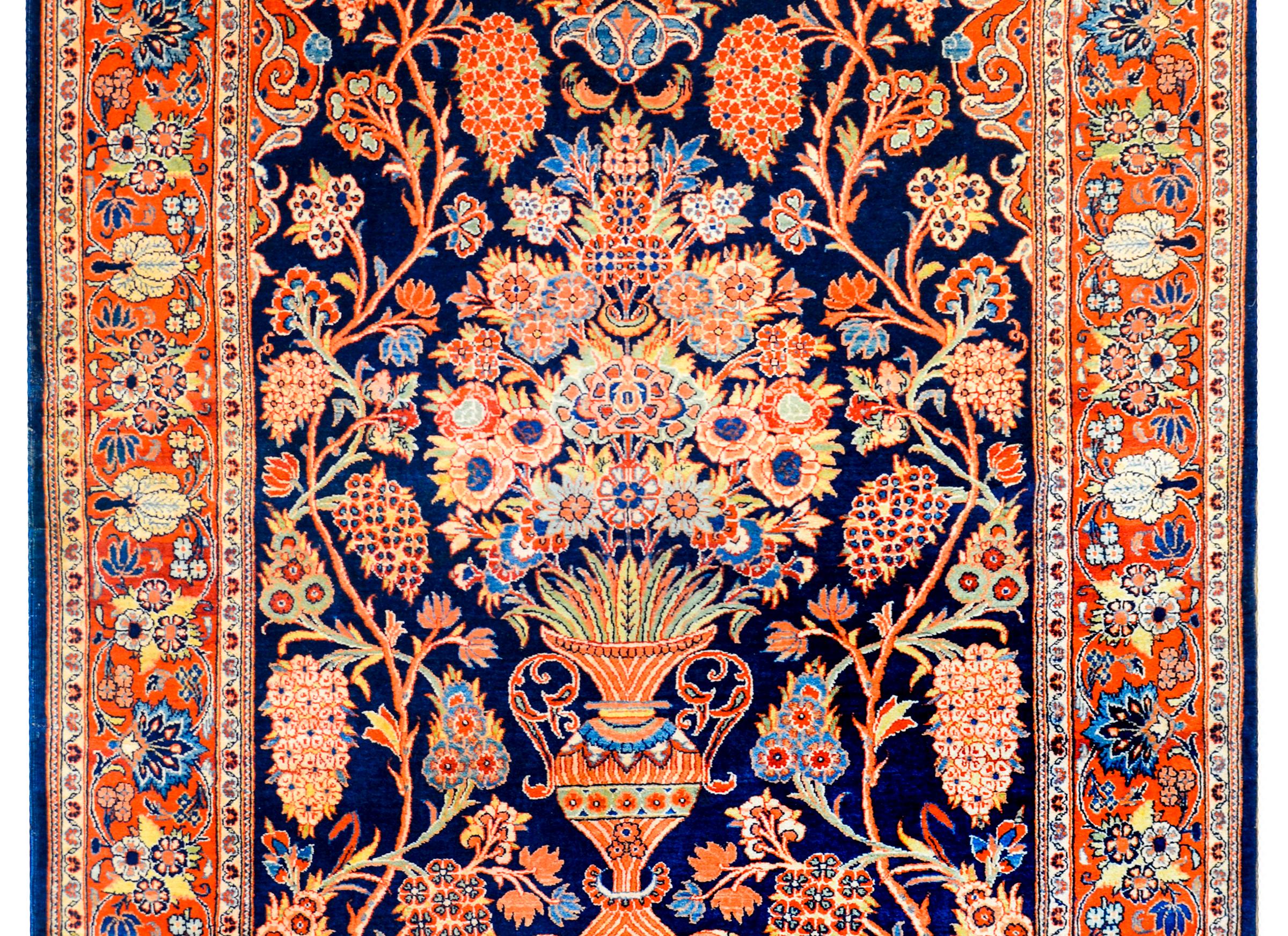 A gorgeous early 20th century Persian Kashan prayer rug with a wonderful central vase potted with a larger-than-life tree-of-life pattern woven in multicolored vegetable dyed wool on a deep indigo background. The border is wide, with a complimentary