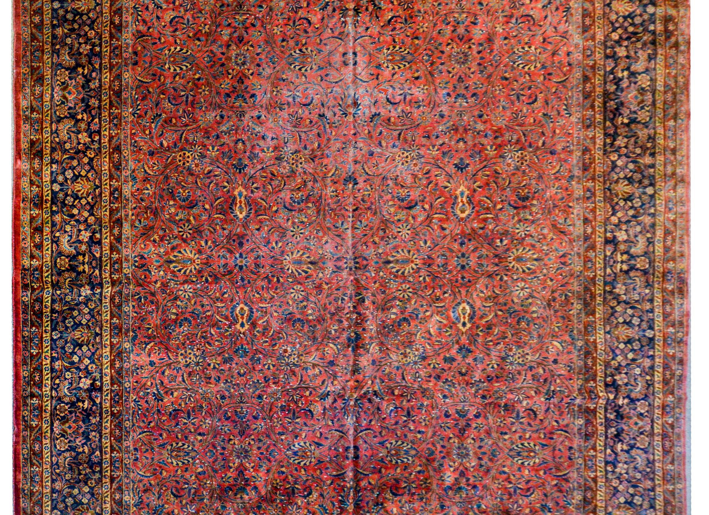 A gorgeous early 20th century Persian Kashan rug with a fantastic all-over mirrored floral and vine pattern woven in light and dark indigo, cream, pink, and gold vegetable dyed wool. The border is wonderful with a wide central floral and vine stripe