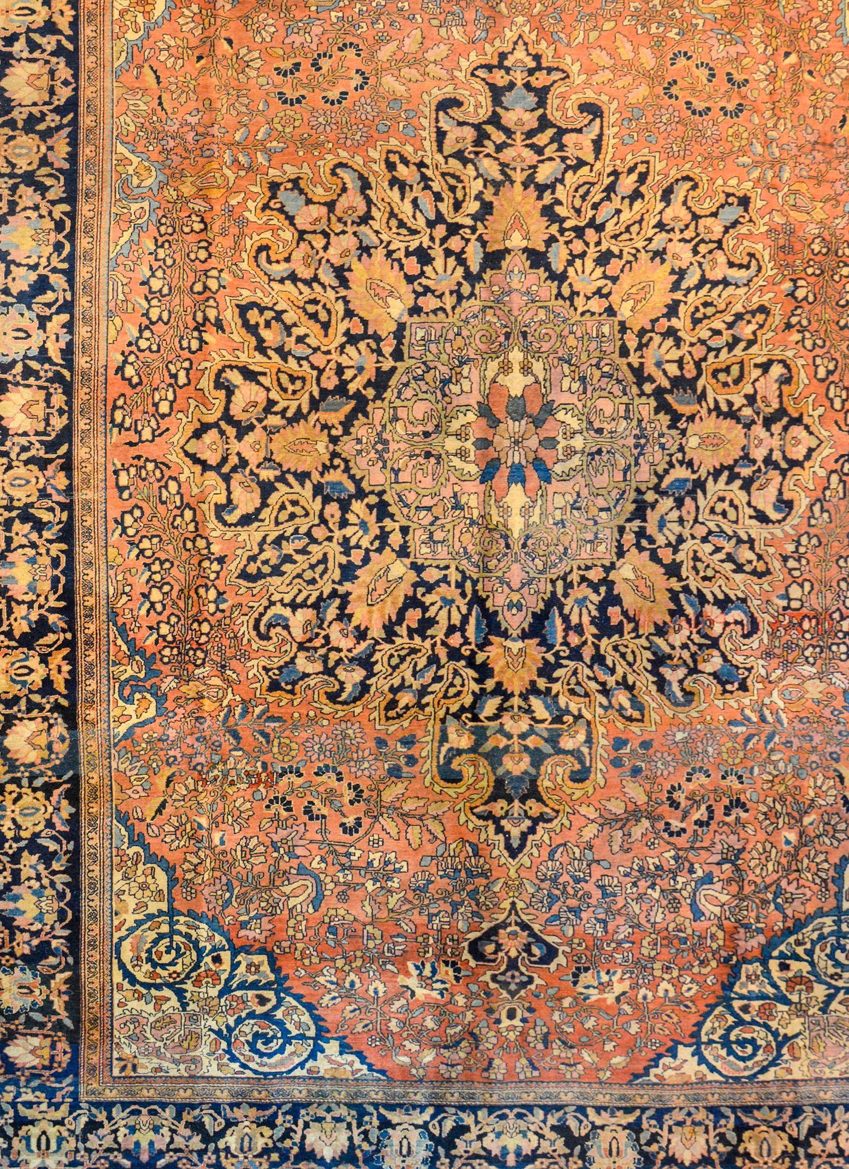 A gorgeous early 20th century Persian Sarouk Farahan rug with a large elaborate central medallion with central flower and myriad vines radiating out from the center. The medallion lives amidst a field of densely woven flowers and vines, all woven in
