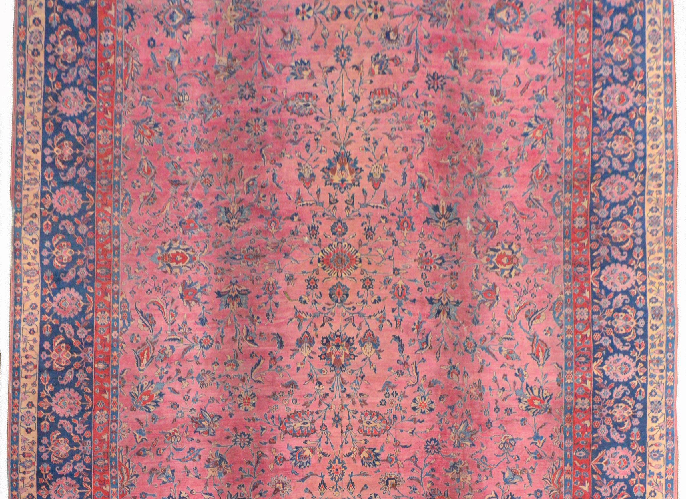 A gorgeous early 20th century Persian Sarouk rug with a fantastic fine all-over large-scale floral and scrolling vine pattern woven in light and dark indigo, coral, brown, against an abrash fuchsia background. The border is extraordinary, with a