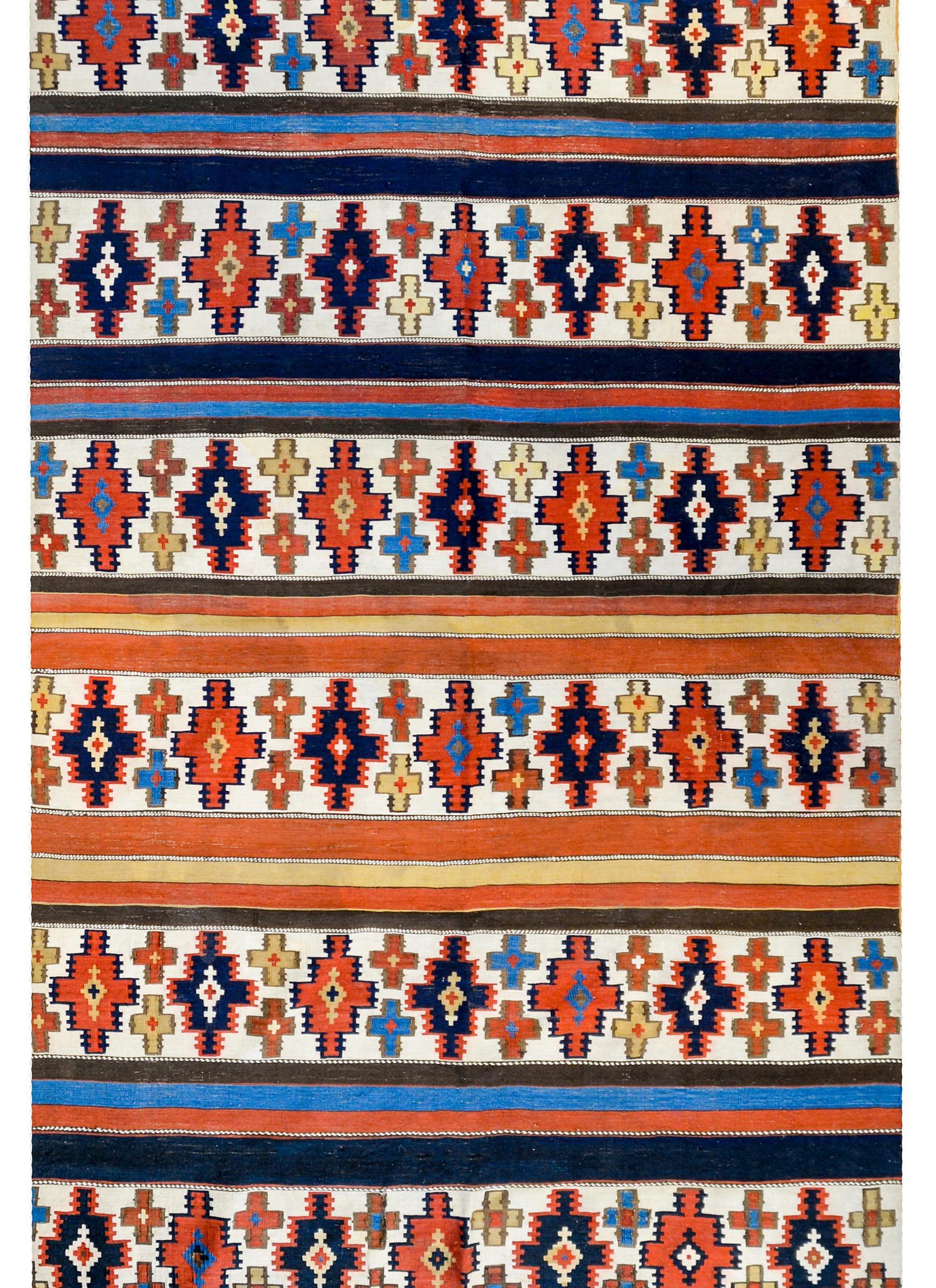 A gorgeous early 20th century Shahsevan Kilim runner with an all-over stepped diamond striped pattern woven in bold crimsons, indigos, gold’s, and browns, with alternating solid colored stripes in between.