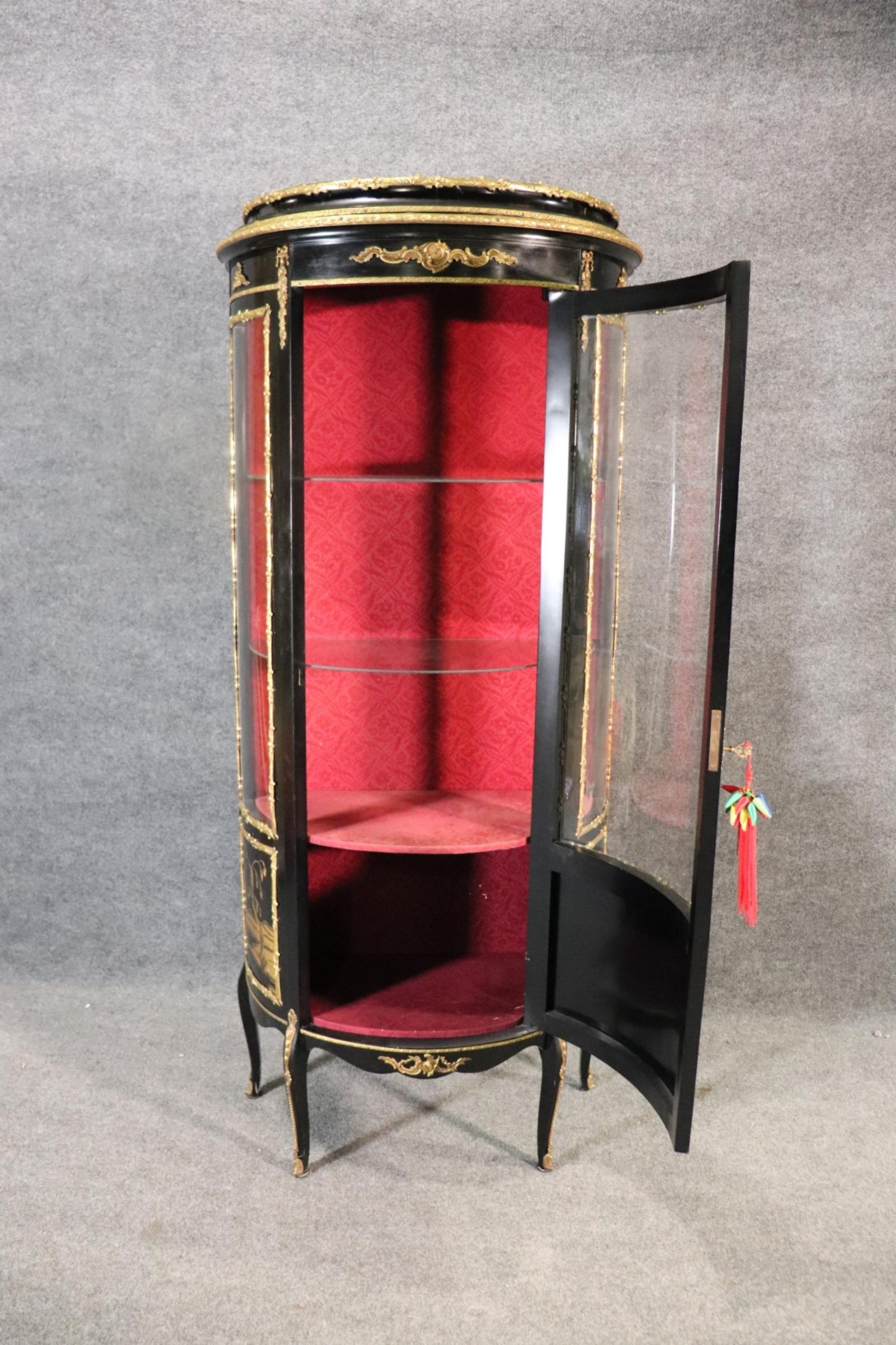 This is a gorgeous ebonized chinoiserie vitrine. The virtine is French-made and in the Louis XV style and is in good condition with a beautiful gold chinoiserie scenic painted design and superb bronze ormolu. The shelves are glass and the doors are