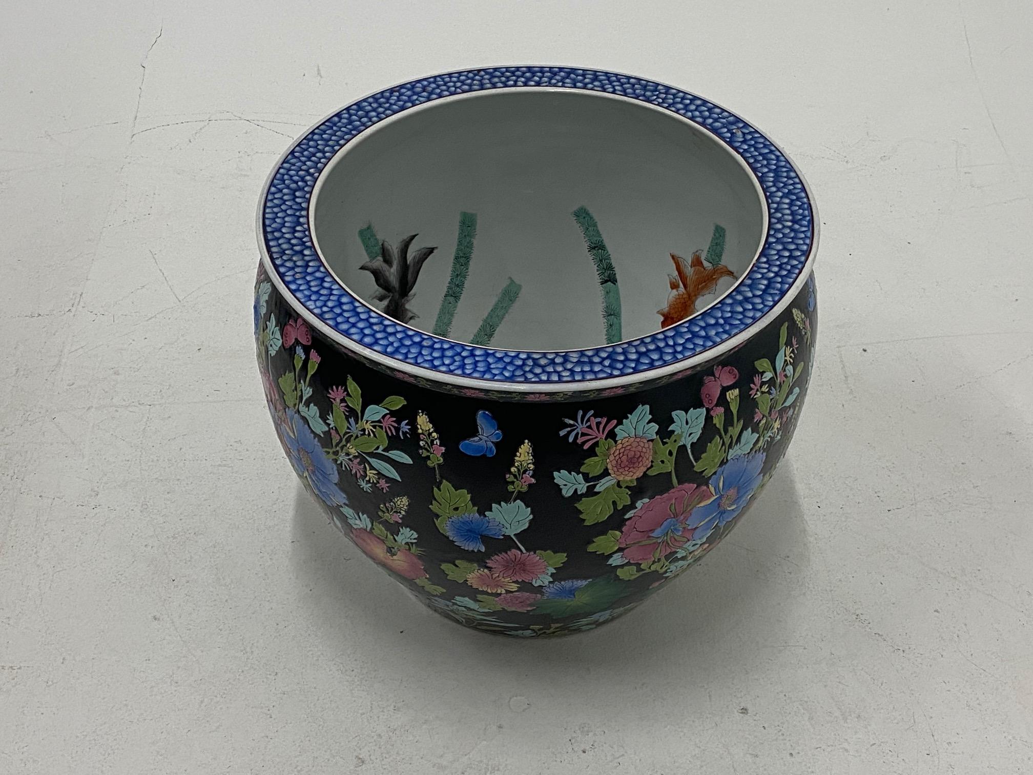 Gorgeous Chinese porcelain fish bowl having striking black background on the exterior with elaborate floral decoration and koi fish with bamboo against white on the inside. The rim is a wonderful contrasting blue and white pattern.
Opening is 15