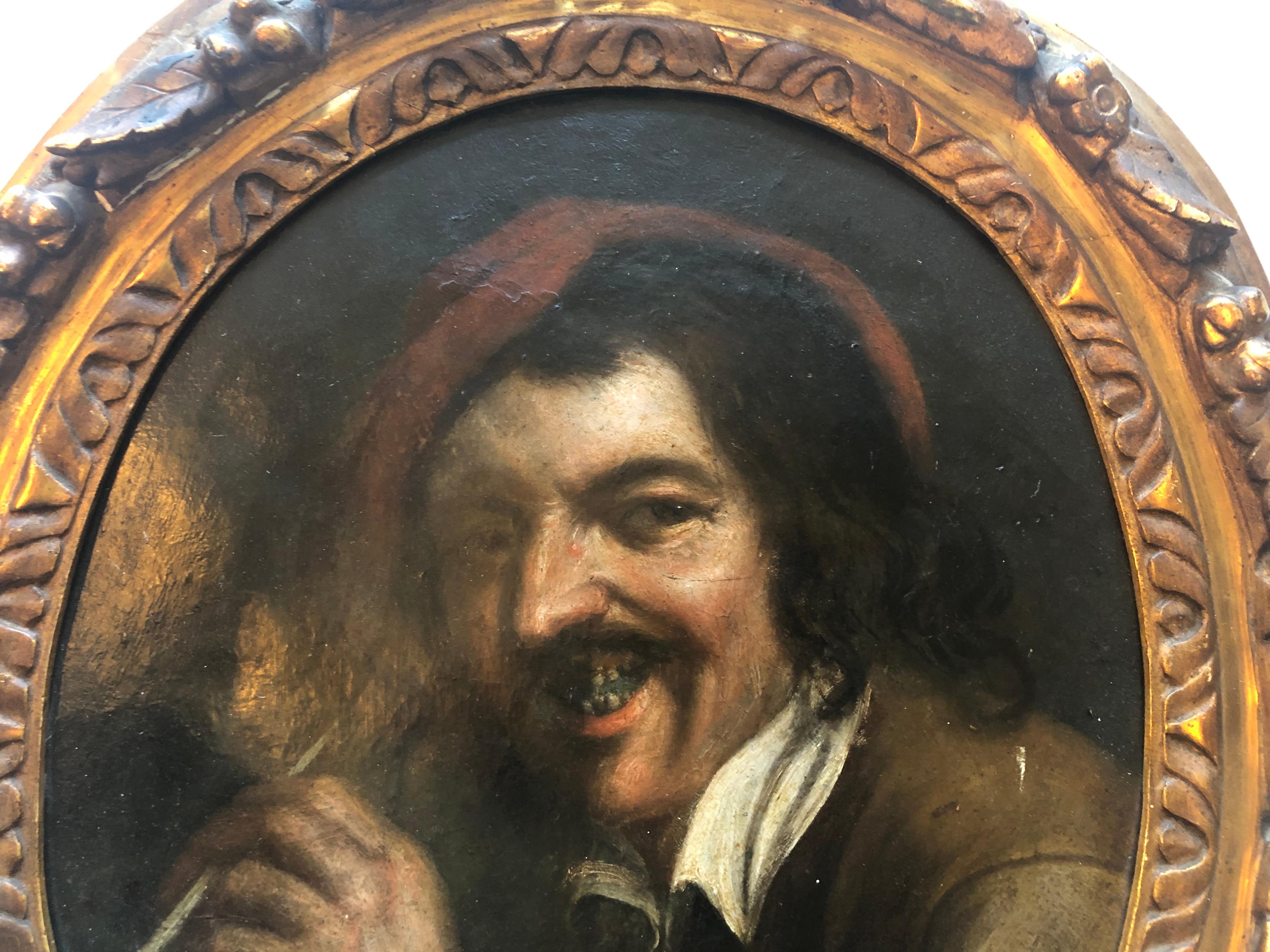 This is a framed 1700s Flemish oil on canvas painting representing a pipe smoker of that time. The oval wooden gilded frame is a stunning work of art itself, carved with leafs, nuts, flowers and scrolls. The artist is unknown, but the quality of the
