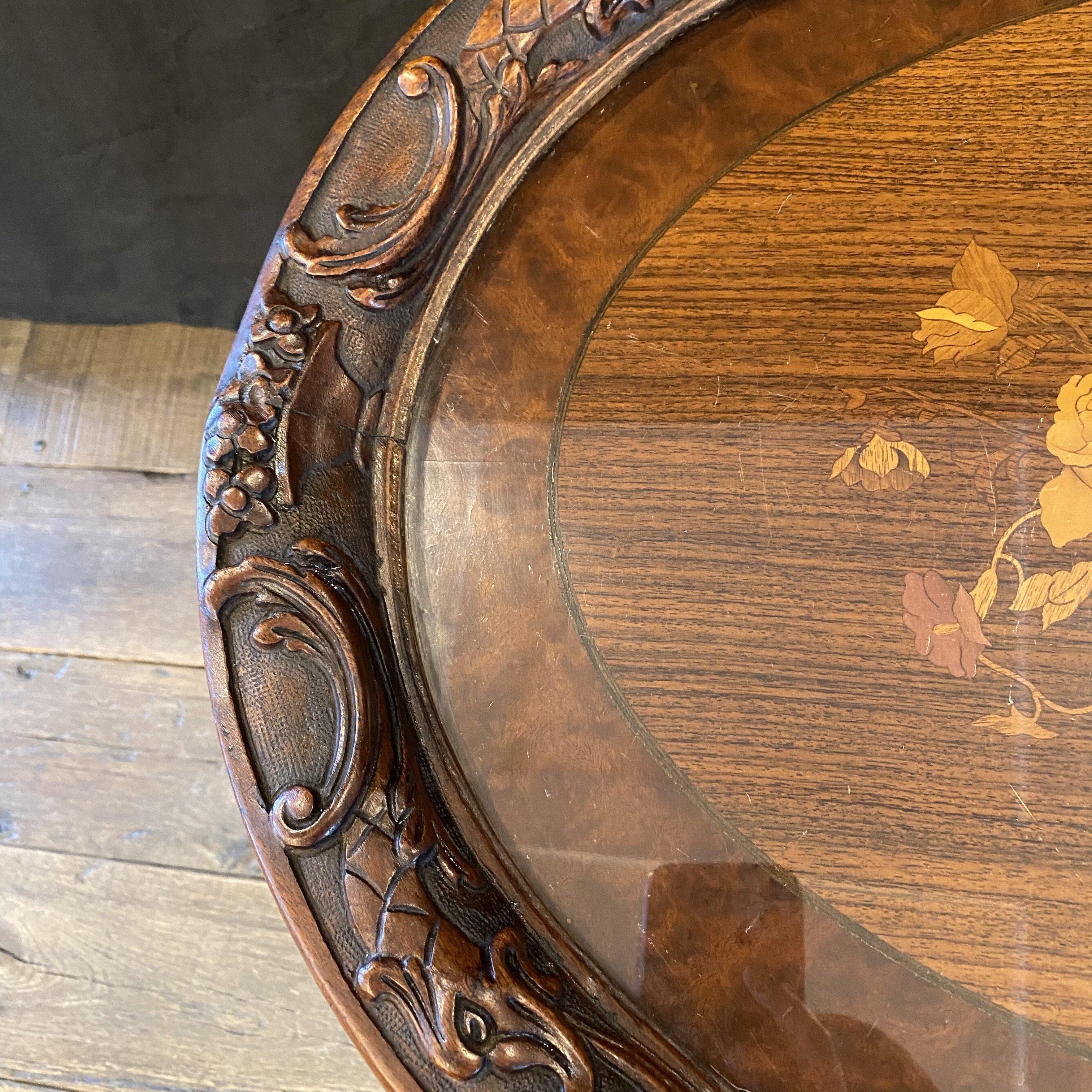 Lovely French Louis XV intricately carved walnut side table or petite oval coffee table having gorgous inlay floral marquetry decoration. Base has marvelous carving and central finial accenting the stretcher underneath. Versatile in its design; can