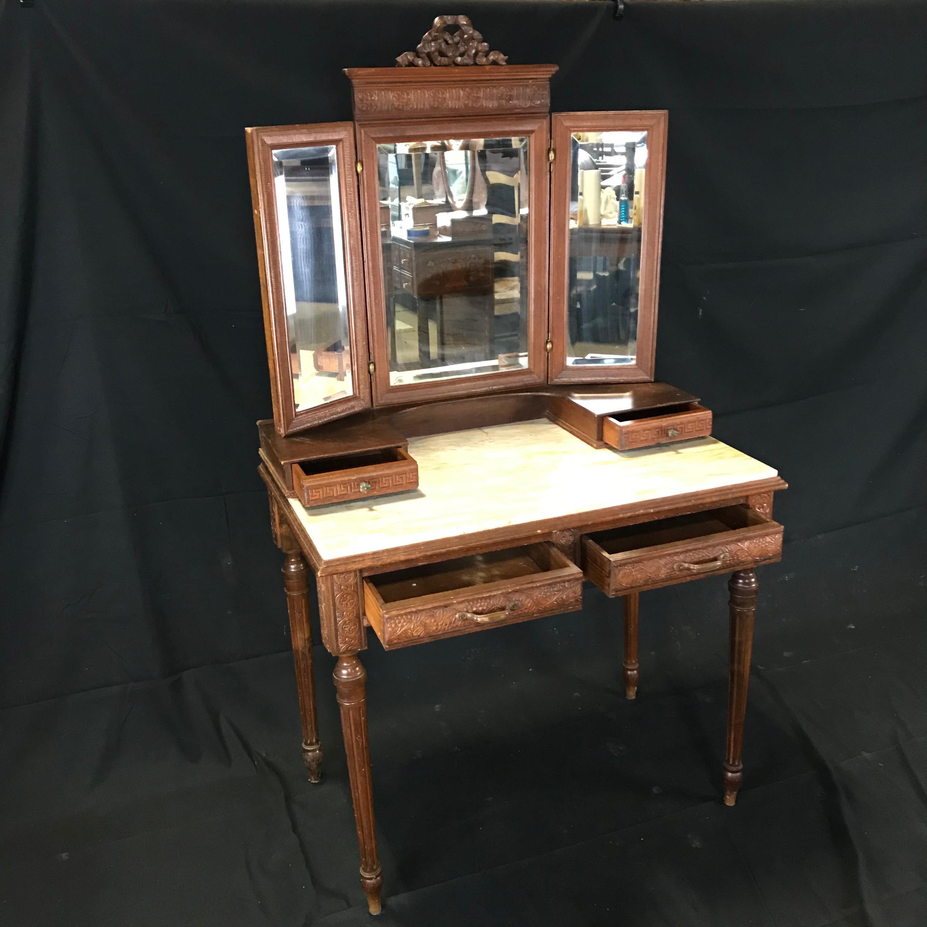 Carrara marble topped French dressing table with beveled mirrors, the side mirrors moveable, with two small drawers on the desktop and two drawers underneath the tabletop, carved walnut frieze and reeded tapering legs. 
 
#4802
Measures: H desk