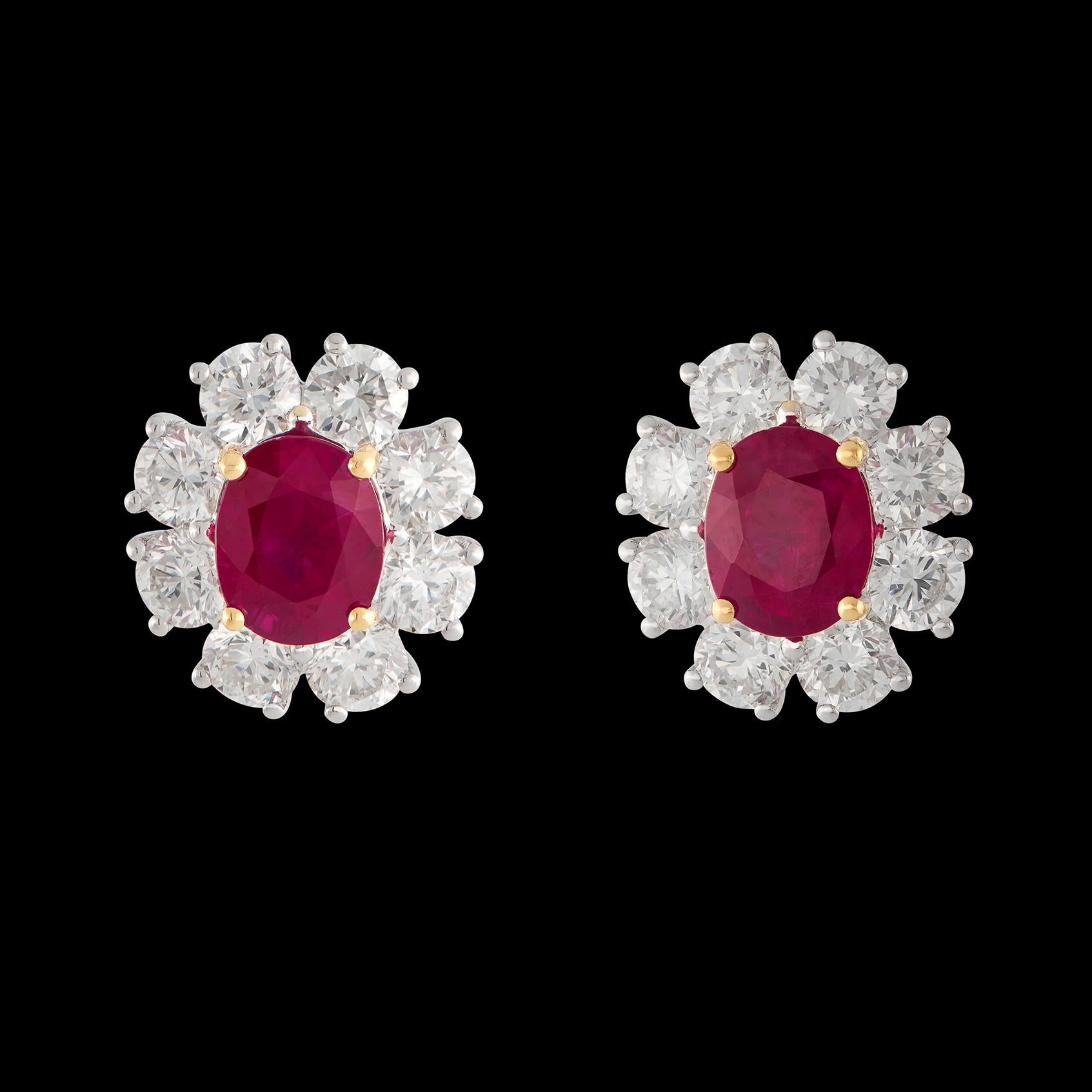 Les boucles d'oreilles de conception classique présentent deux rubis de Brilliante de forme ovale, pesant ensemble 3,85 carats, entourés de 16 diamants ronds étincelants de taille brillant. Les diamants pèsent au total 3,20 carats, sont bien taillés