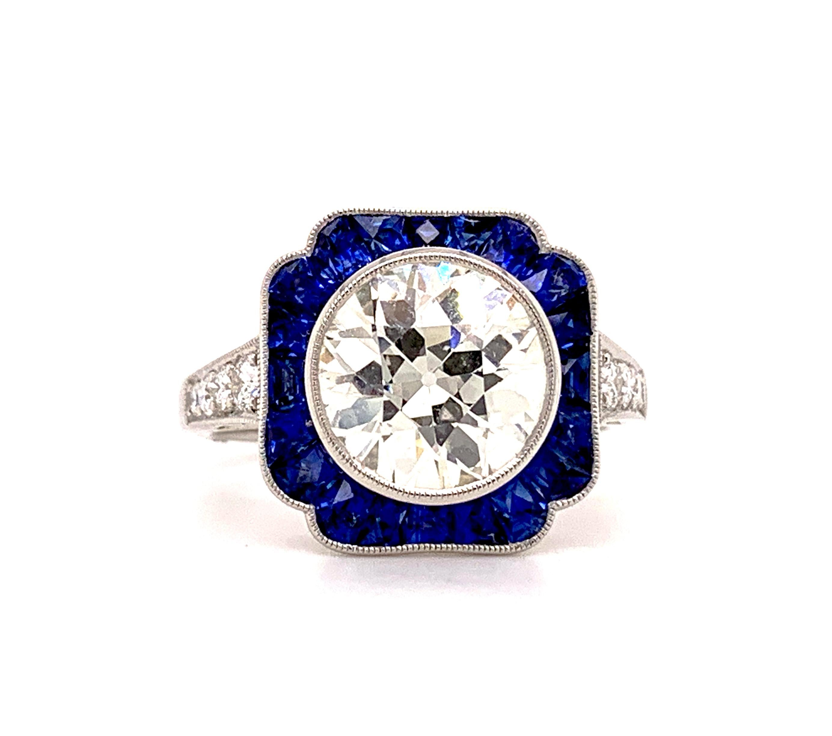 Art deco inspired ring set in platinum made with Old European Diamond center weighing 2.53 carats with a color and clarity of M-SI1 surrounded with blue sapphires weighing 1.15 carats and 0.19 carats of diamonds. 

Sophia D by Joseph Dardashti LTD