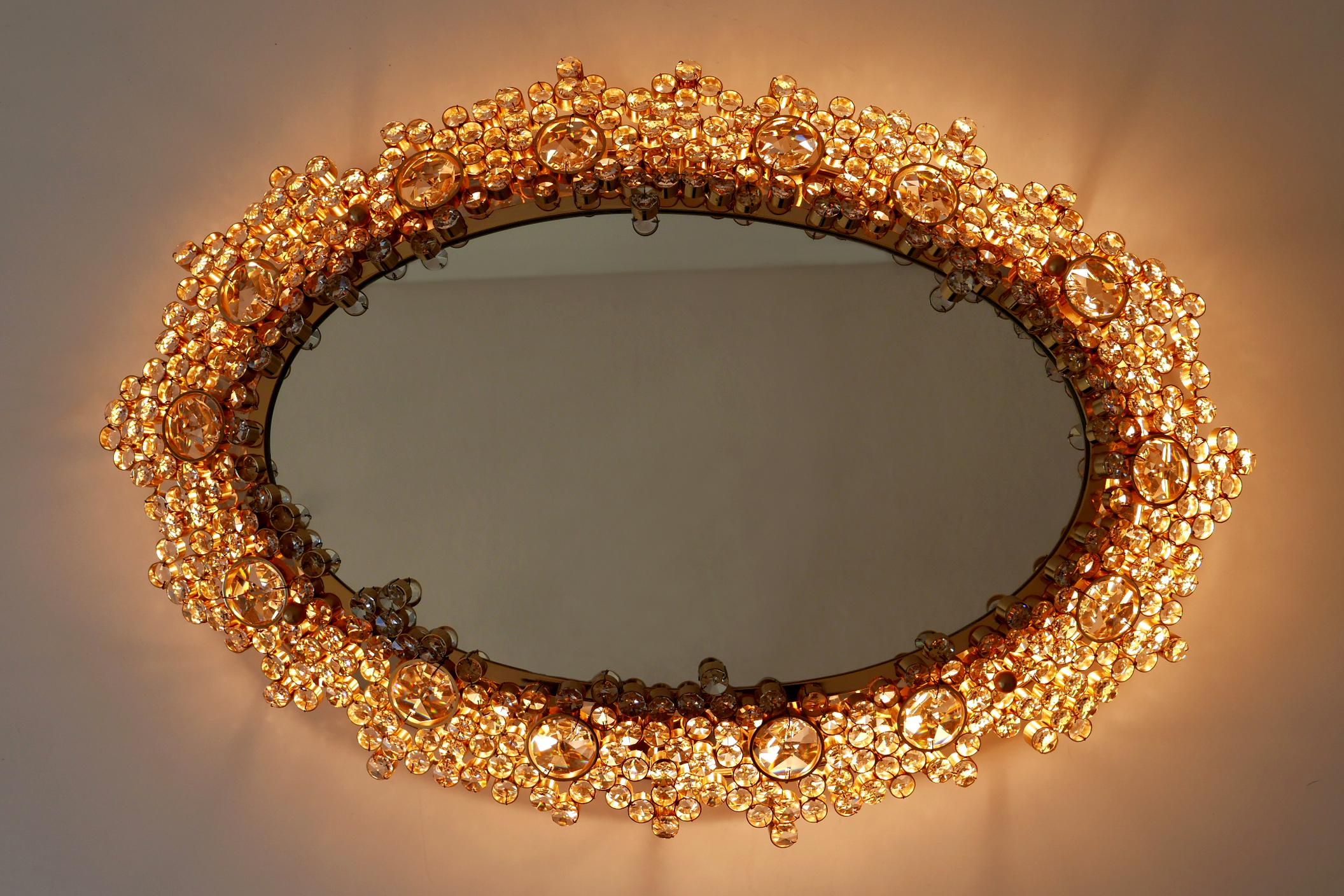 It will be a real gem at your home! Spectacular, elegant & large Mid-Century Modern oval backlit wall mirror. Designed & manufactured by Palwa, Germany, 1970s.

Executed in gilt brass and hundreds of facet-cut crystal glass elements, the mirror