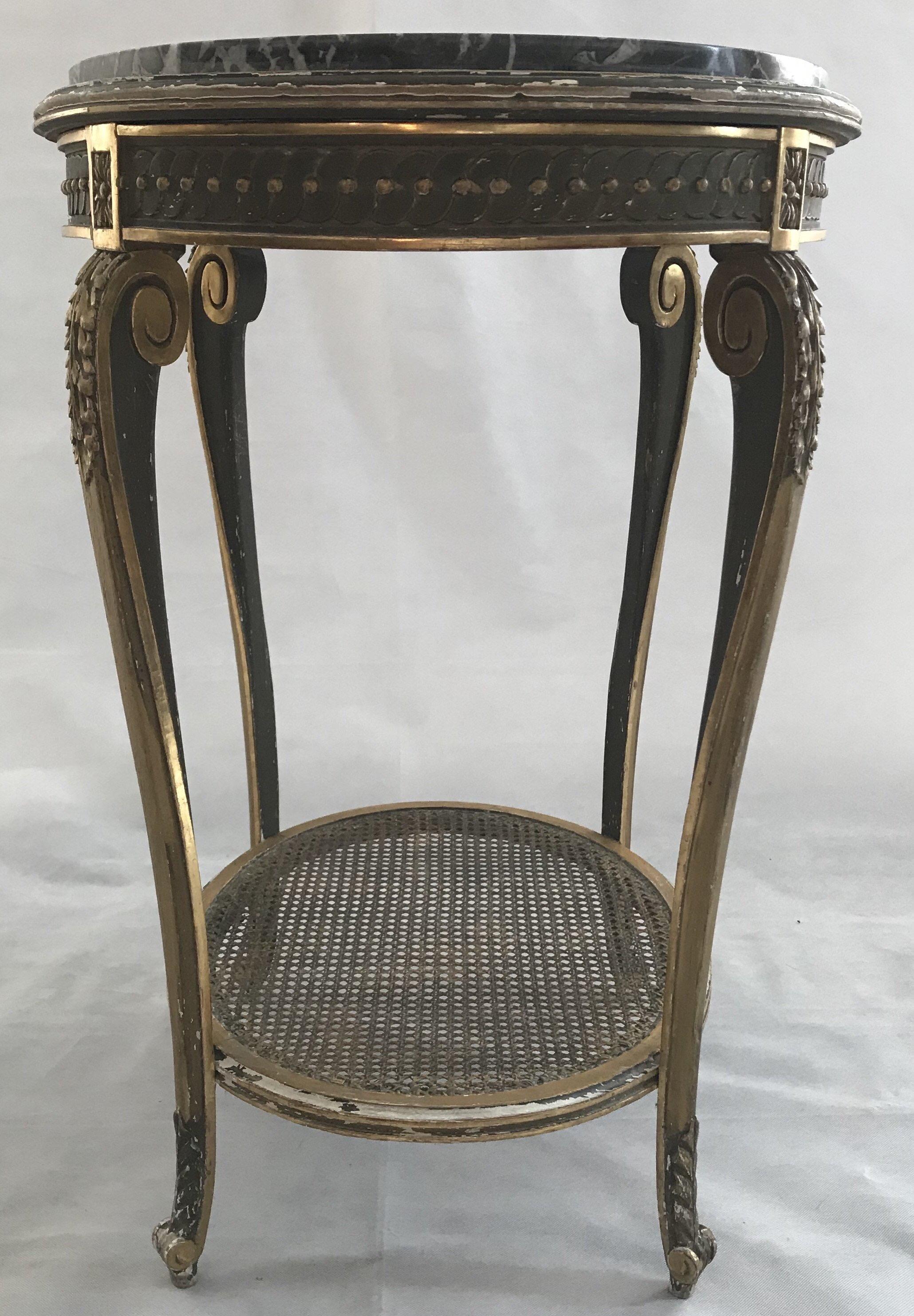 An unusually pretty French antique giltwood oval side or accent table with lively black and white marble top and caned bottom tier.

#2334.