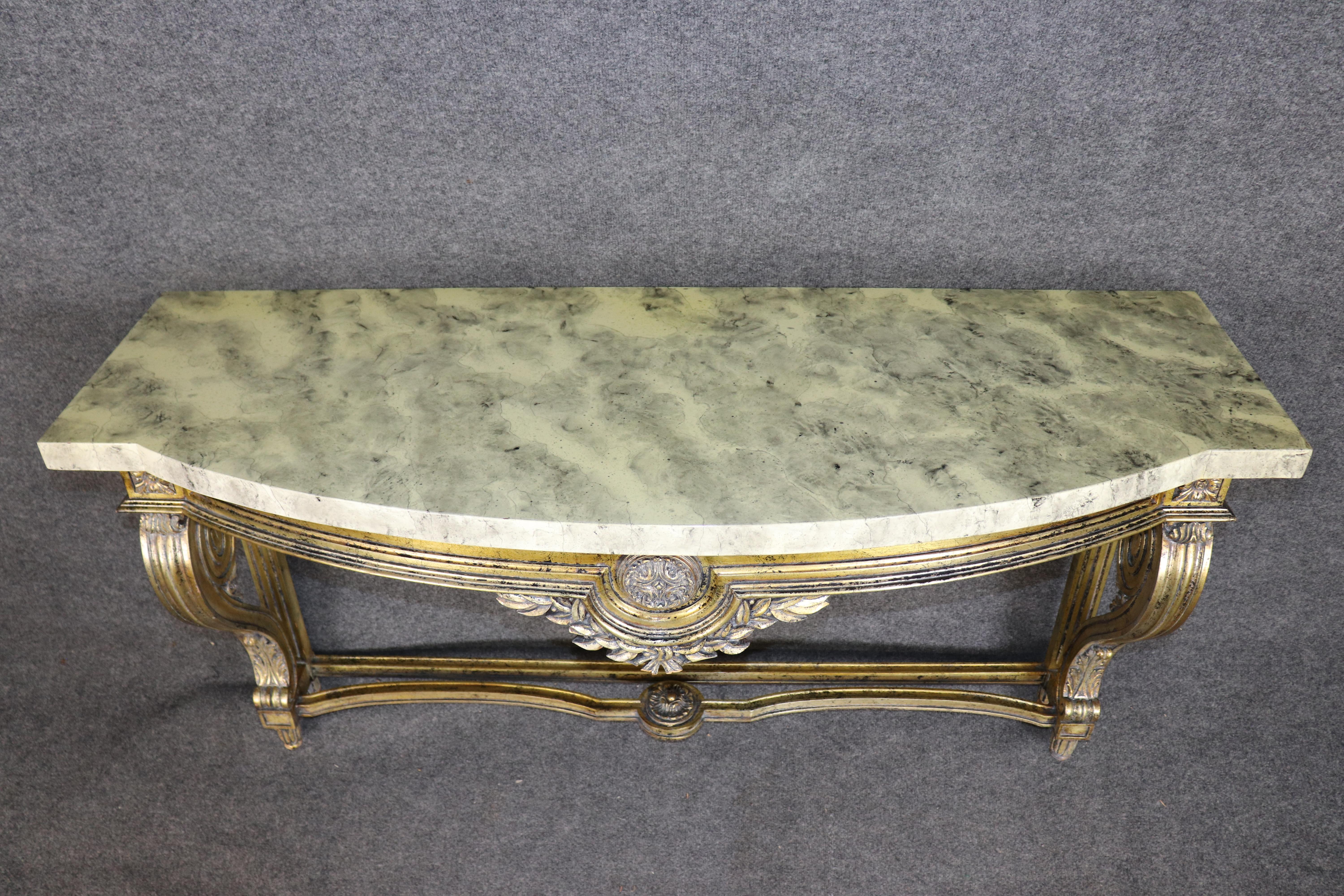 This magnificent French Louis XV style gilded console table captures the grandeur and refinement of 18th-century Parisian design. The table’s curvaceous silhouette, fluted cabriole legs, and floral medallion carvings showcase exceptional