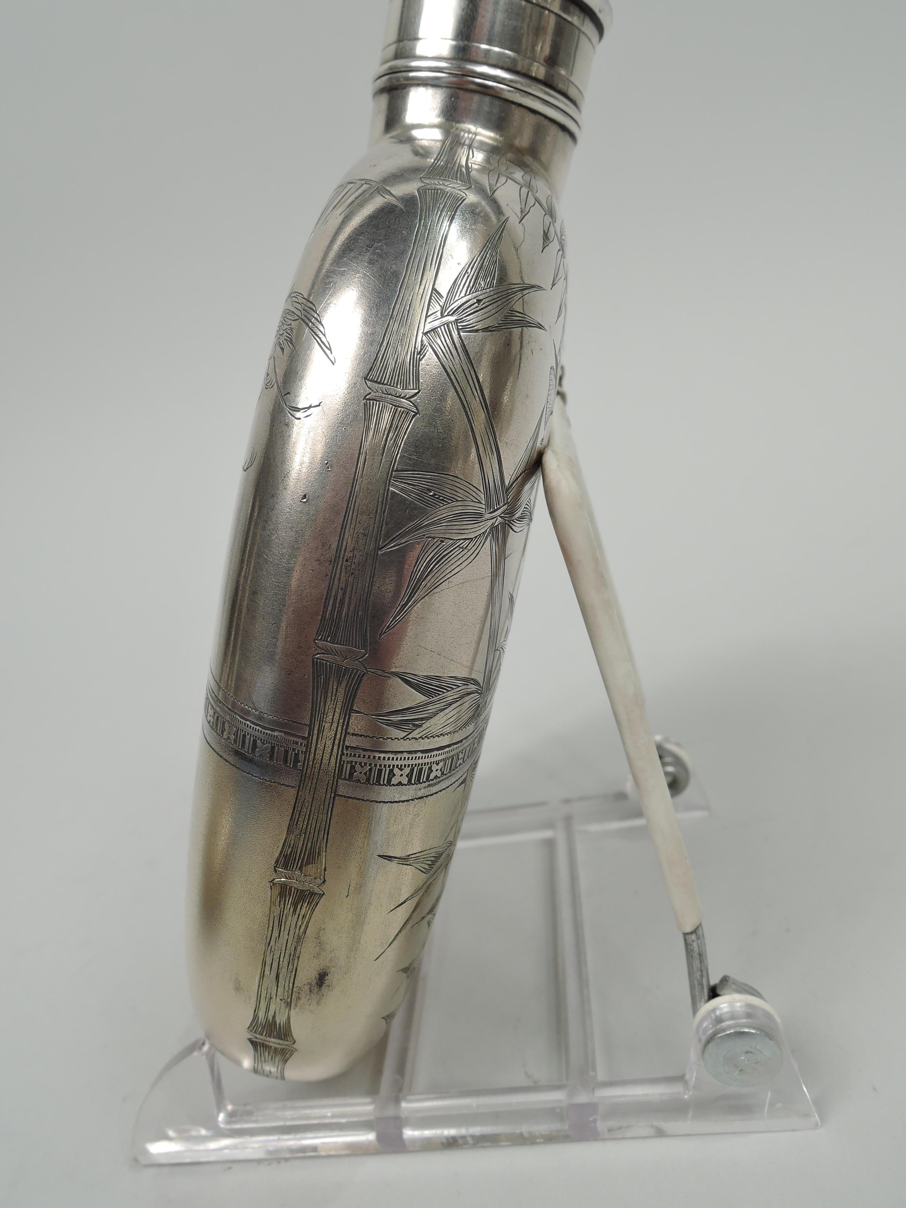 Japonesque sterling silver flask. Made by Gorham in Providence in 1878. Ovoid with flat front and back, short neck, and chained, threaded, and cork-lined cover. Engraved bamboo, cranes, butterflies, and pavilions. Bottom cup detachable to reveal