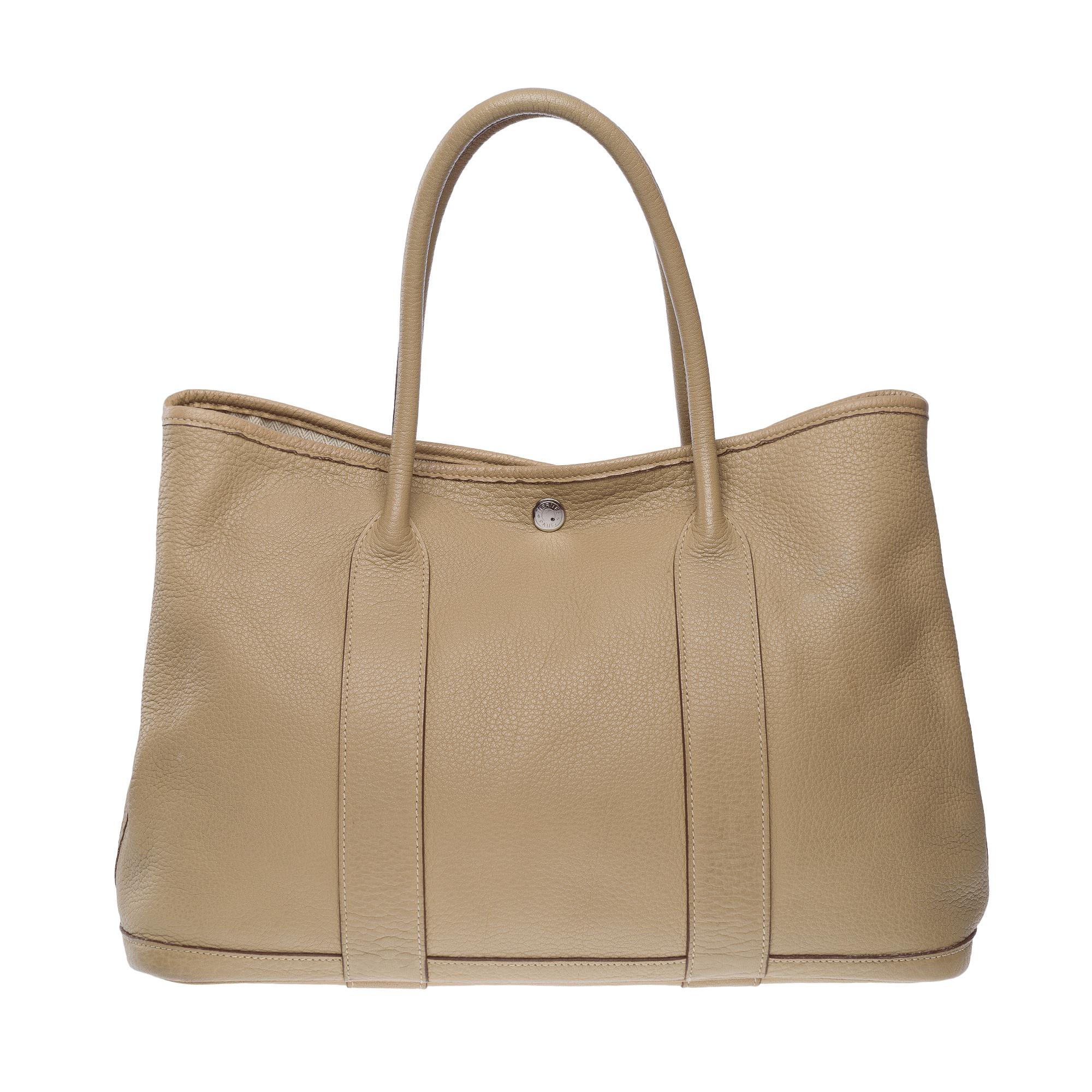 Beautiful​ ​Hermès​ ​Garden​ ​Party​ ​36​ ​Tote​ ​bag​ ​in​ ​Etoupe​ ​Negonda​ ​calf​ ​leather,​ ​with​ ​double​ ​grey​ ​leather​ ​handles​ ​allowing​ ​for​ ​hand​ ​or​ ​shoulder​ ​carry

Silver​ ​metal​ ​saddle​ ​nail​ ​pattern​ ​snap​