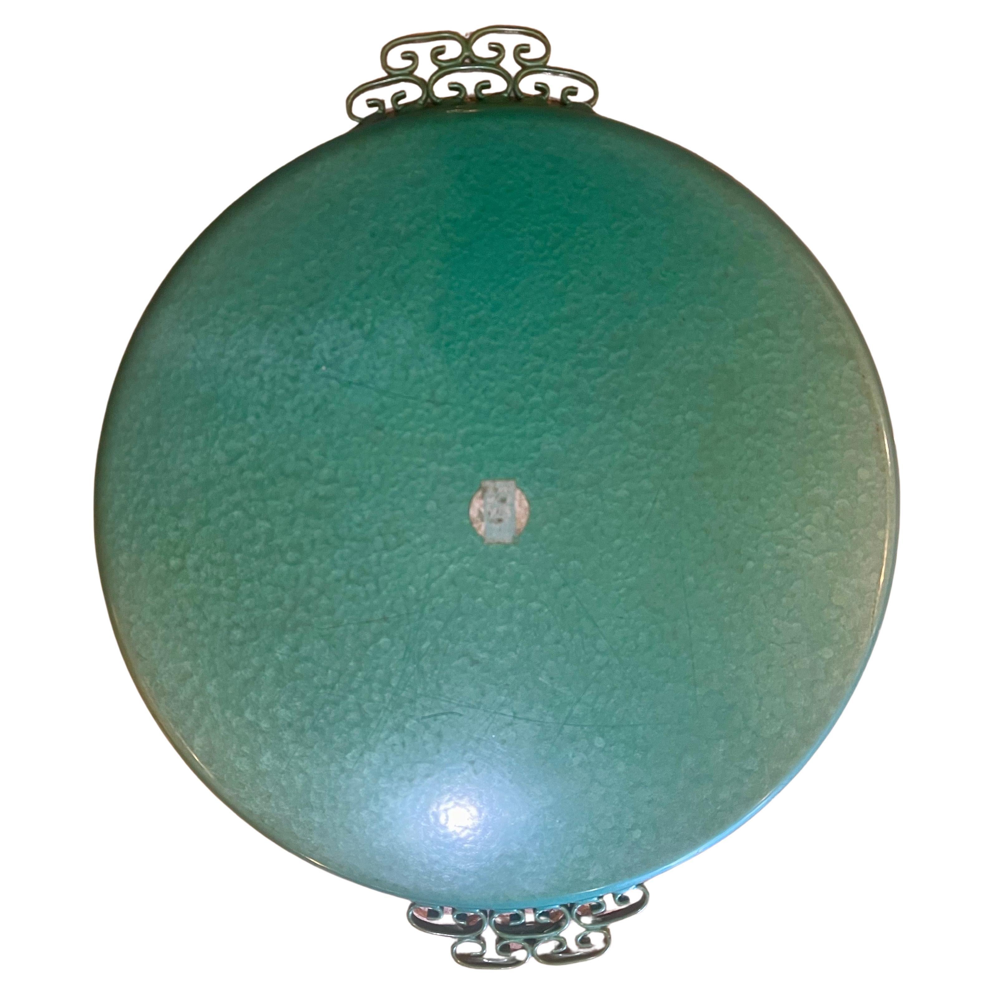 Step into the glamour of Hollywood Regency with this exquisite round metal tray, a true gem from the 1960s handcrafted by the renowned artisan Moire Glaze Kyes in sunny California. This tray is more than just a functional piece; it's a work of art