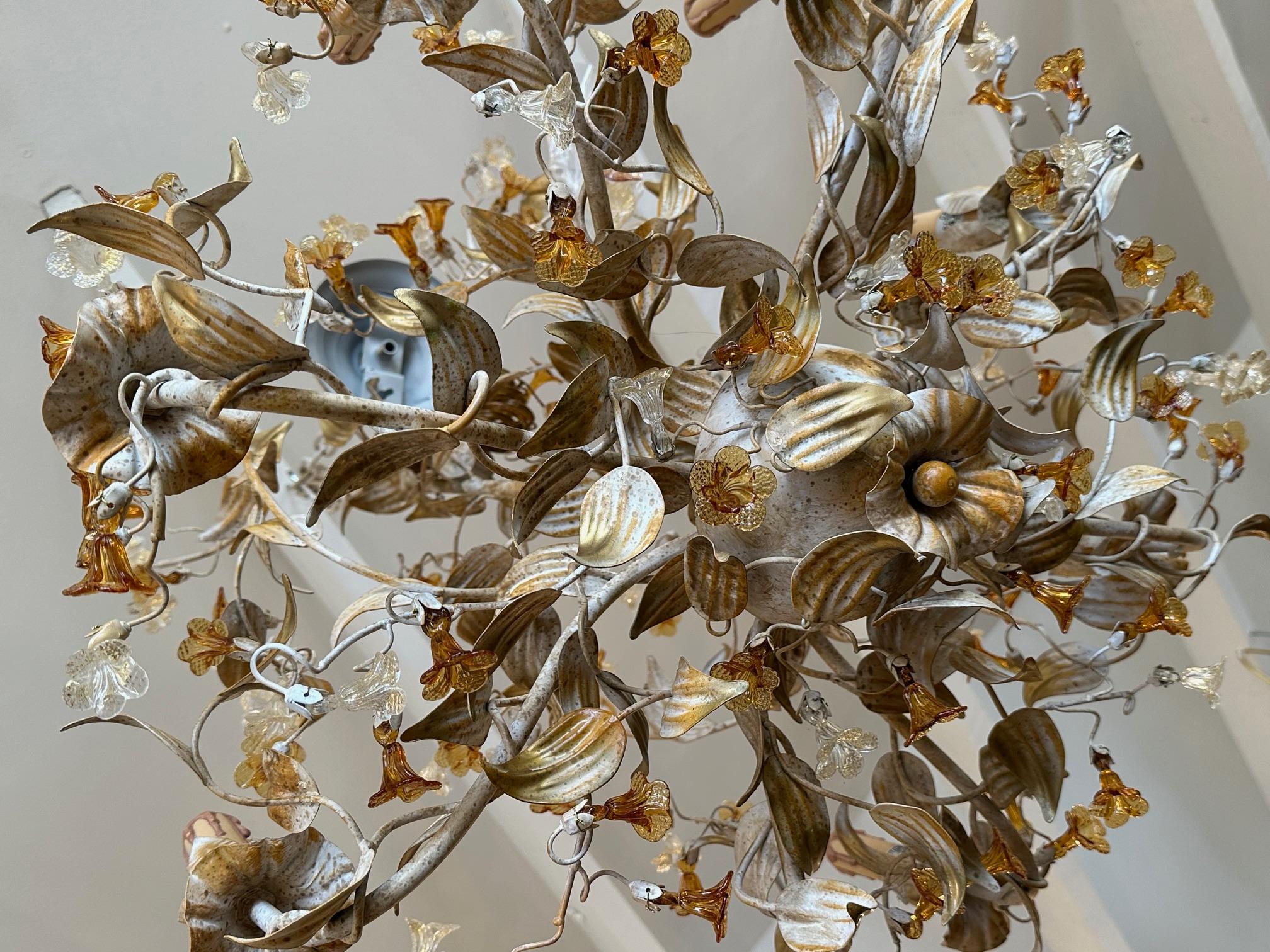 Elegante lampadario italiano contemporaneo a 8 bracci con corpo in metallo verniciato color crema e bracci decorati con scintillanti fiori in vetro di Murano color ambra e trasparente. Da Mechini
