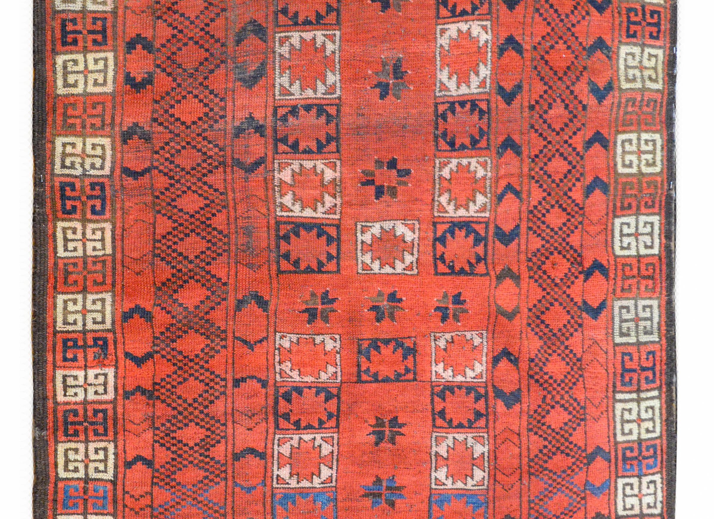 A gorgeous early 20th century Persian Ersari rug with an all-over stylized floral pattered woven in crimson, white, and indigo, against a crimson background, and surrounded by multiple geometric pattered stripes.