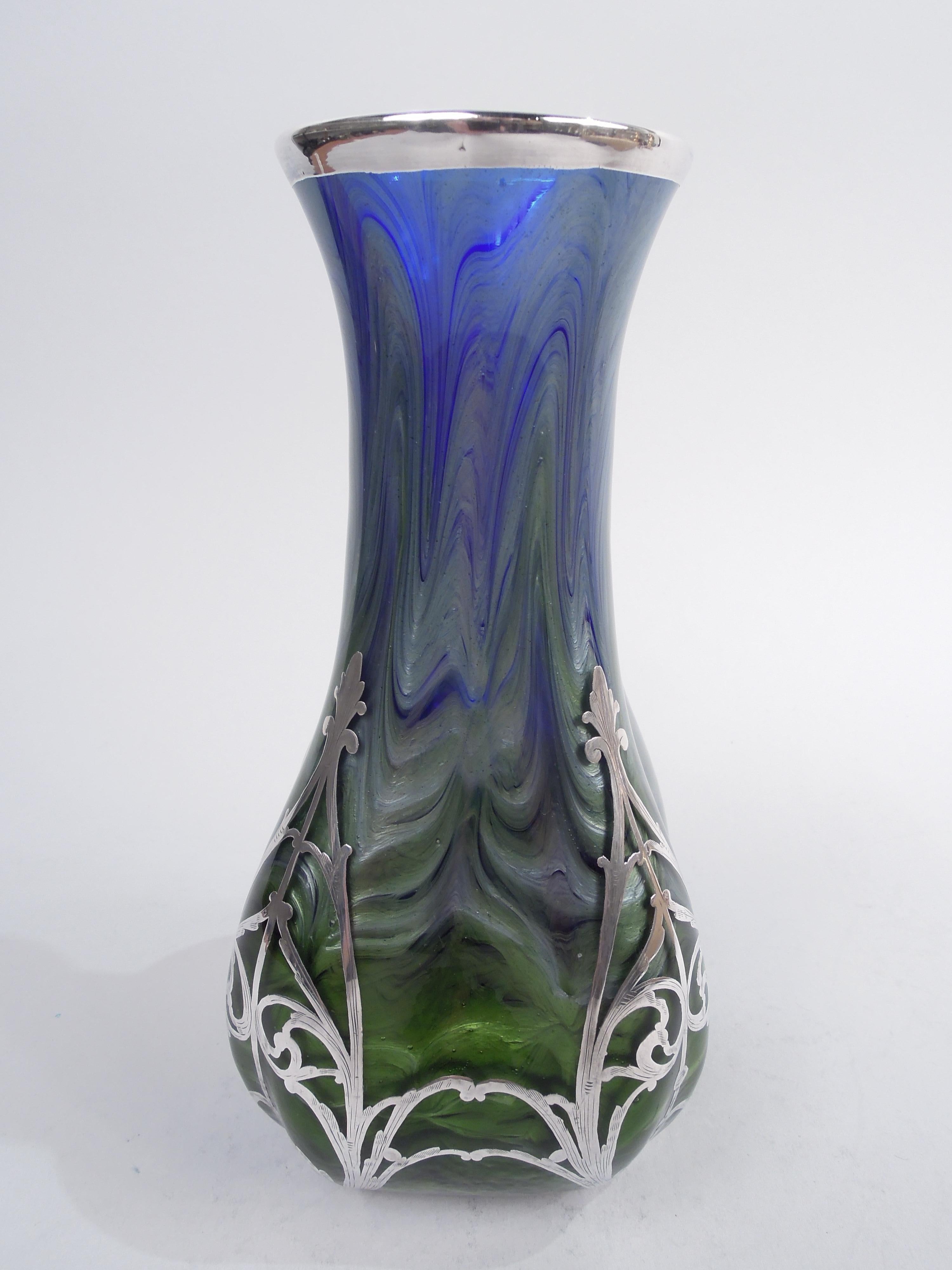 Gorgeous Titania glass vase by historic maker Loetz with engraved silver overlay, ca 1900. Upward tapering sides with gently flared mouth. Sides concave and corners chamfered. Overlay in form of vertical leafing scrollwork mounted at corners and