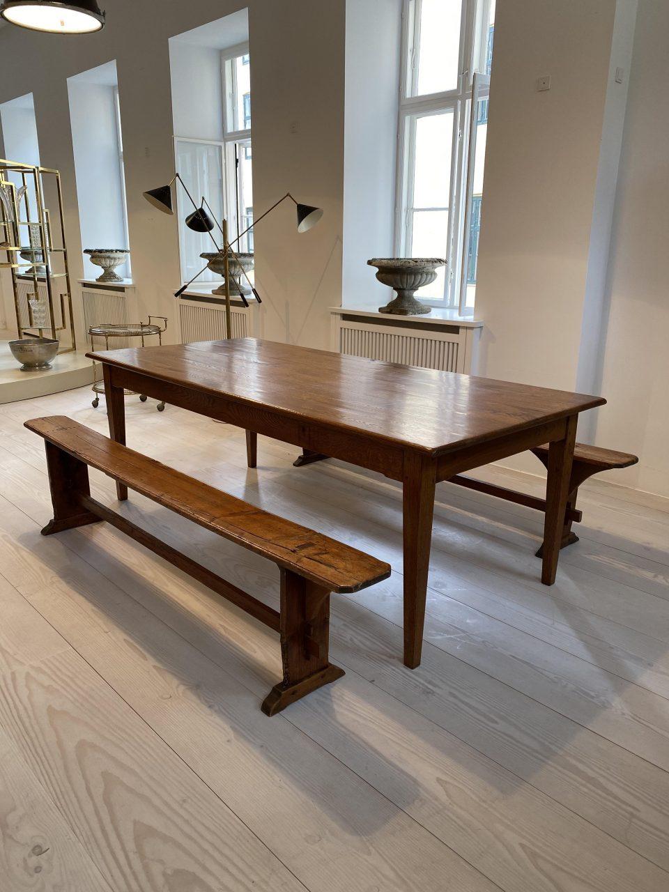 Handsome and good quality vintage long table from southern France. The table features a beautiful quality dark waxed table top that rests steadily on 4 tapered legs. Two narrow and elegant wooden benches in the same style are included in the set,