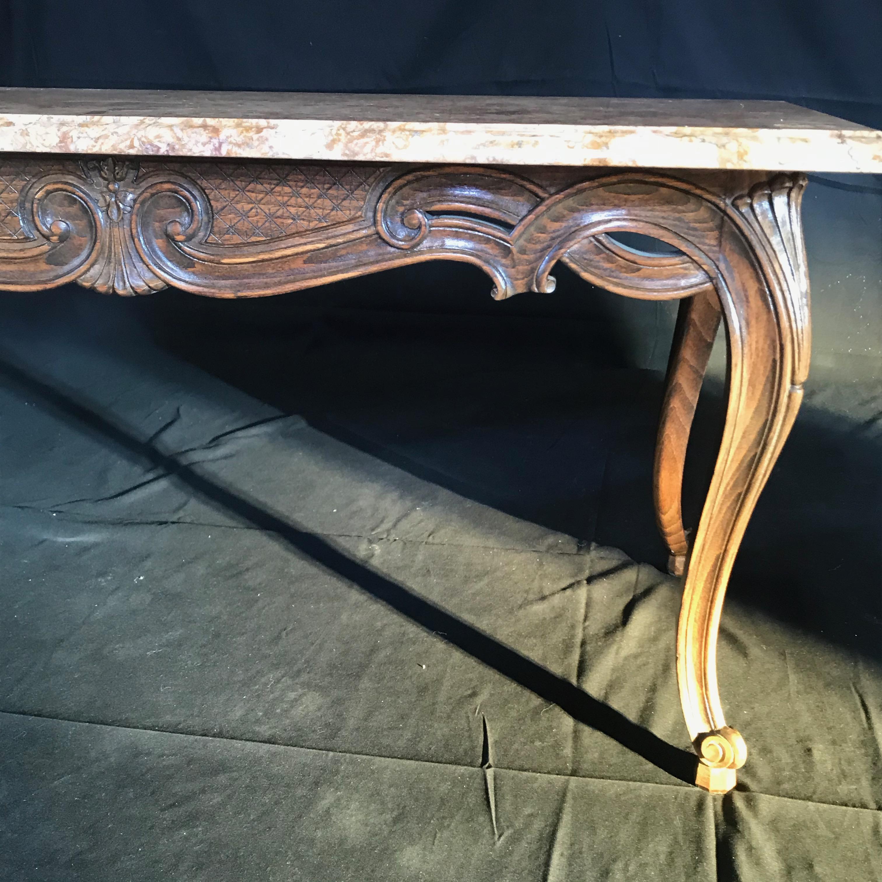 A stunning antique French coffee table having a Louis XV form with an entire walnut frame carved in ribbon design with stunning diamond pattern finely carved into the apron, on tapering legs with snail feet, supporting a beautifully grained neutral