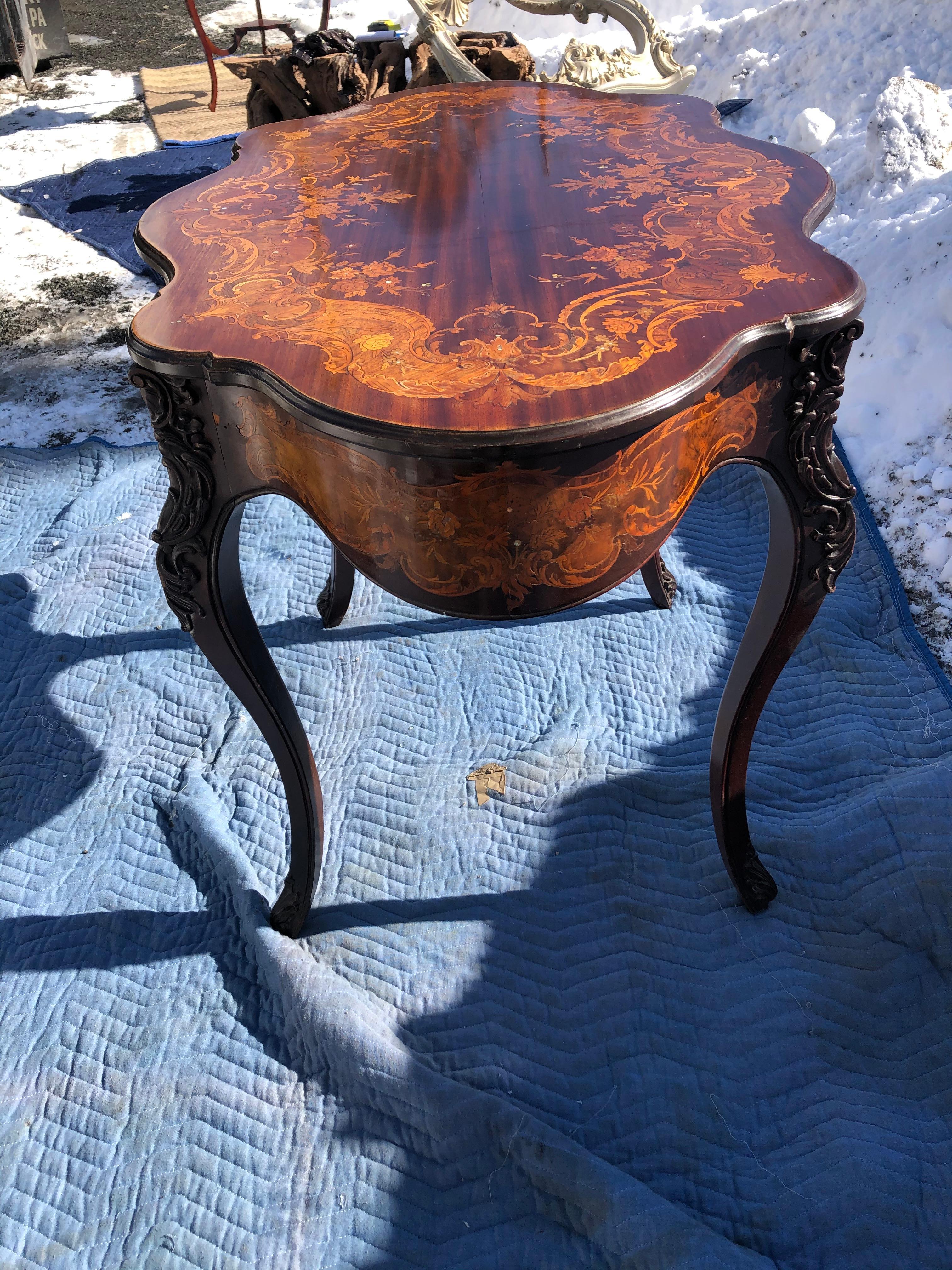 A beautifully shaped marquetry center or side table having serpentine moulded top with scrolling foliate, floral and mother of pearl inlay, and cabriole legs with carved knees.
