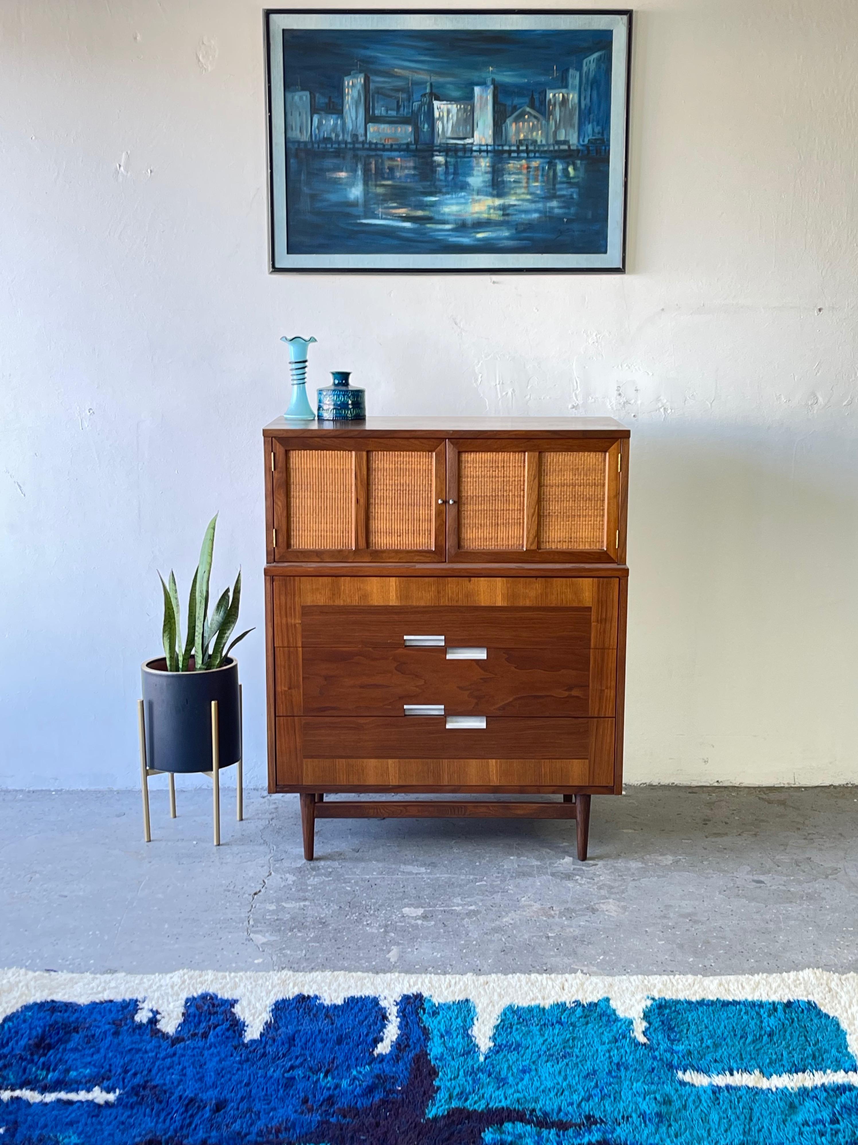 American of Martinsville walnut highboy Mid-Century Modern dresser from their Accord collection. Super cool wicker doors at top of dresser with two drawers inside.

Dresser has 3 drawers as well,

Good storage space with great brushed aluminum