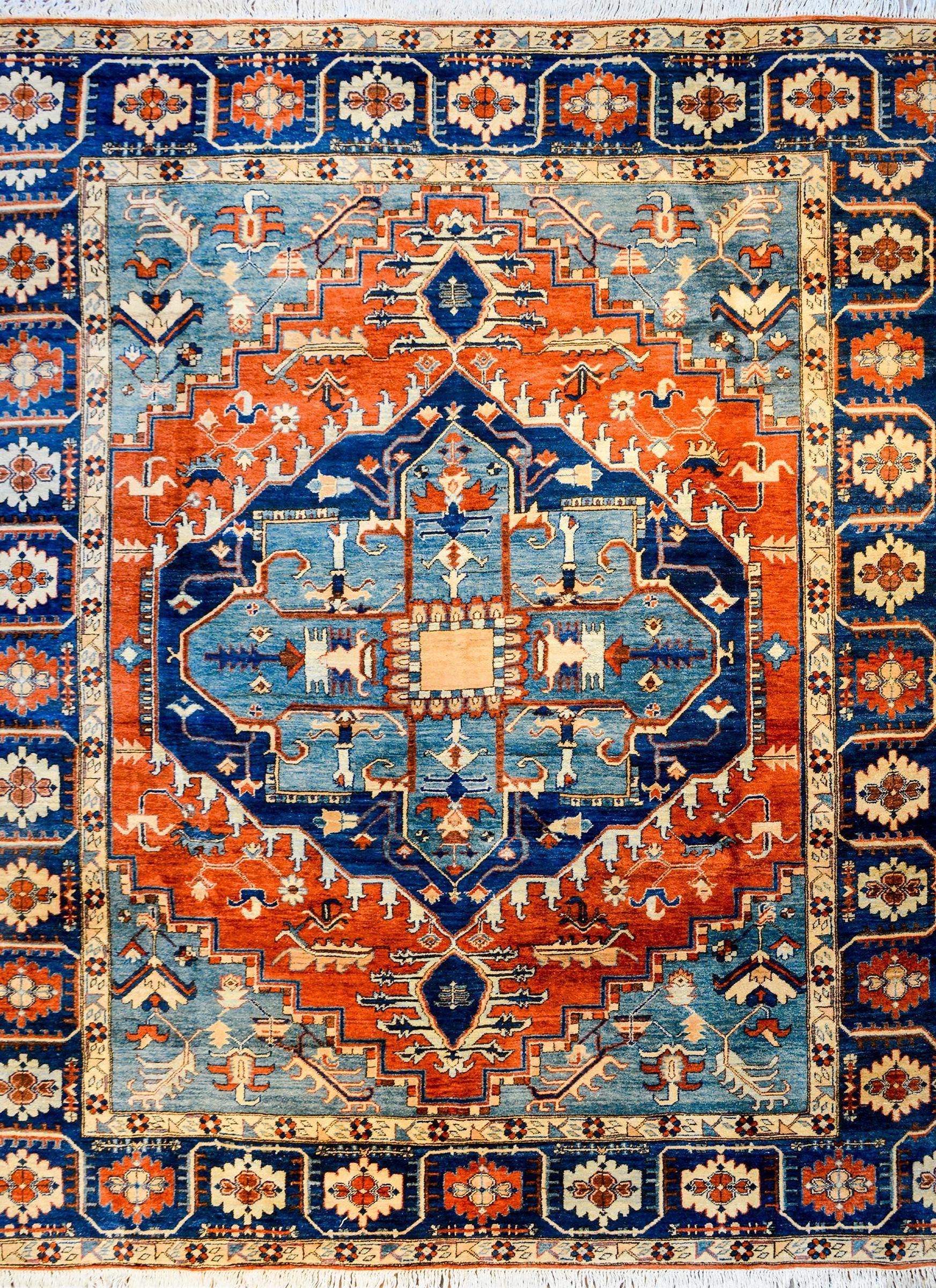 A gorgeous mid-20th century Persian Serapi rug with a large-scale two-tone indigo lobed-diamond with a scrolling vine and floral motif on a bright crimson background. The border is exquisite with a expertly rendered large-scale stylized floral and