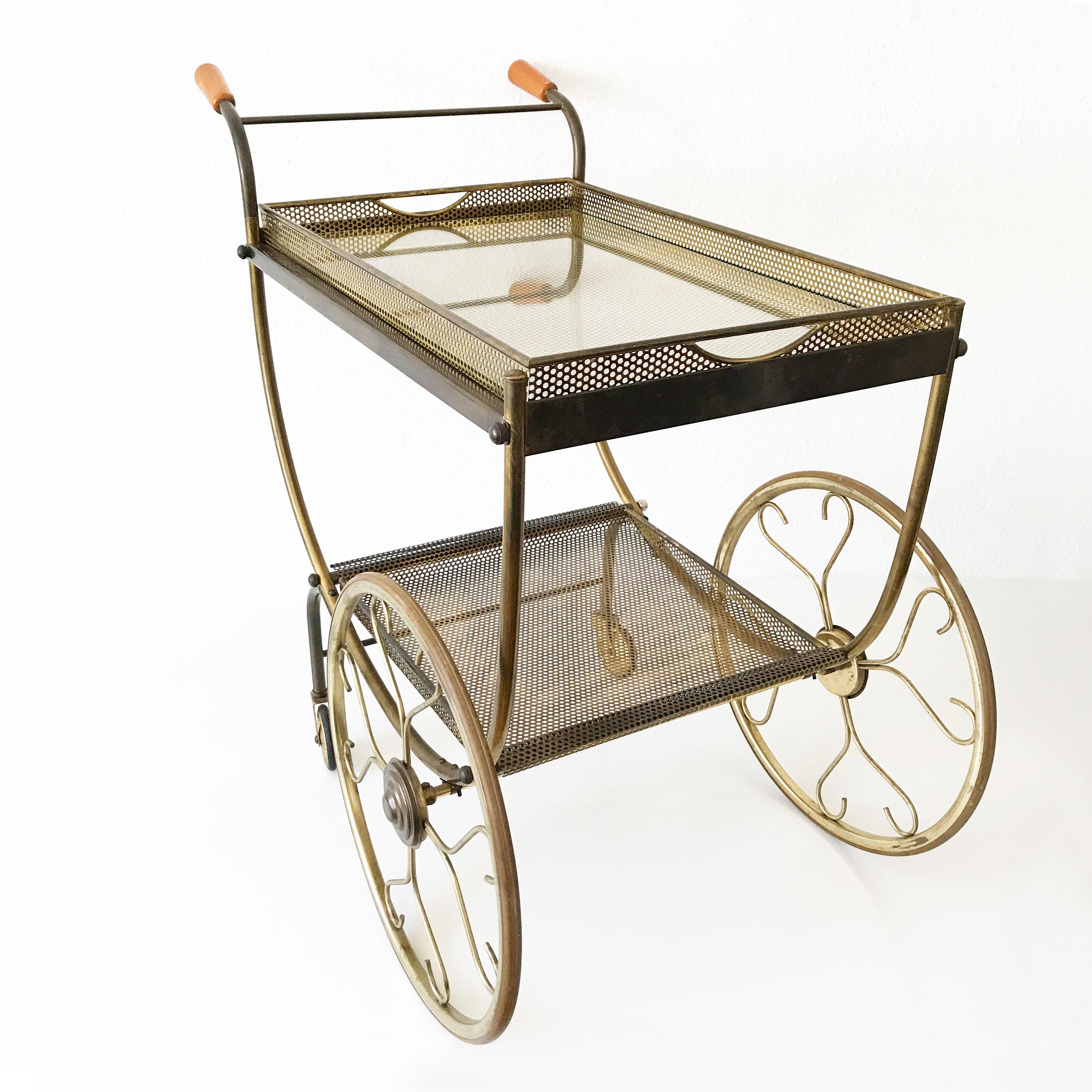 A rare and highly decorative Mid-Century Modern bar cart or tea trolley with elegant details and two removable serving plates. Designed and manufactured in 1950s by Svenskt Tenn, Sweden.

Executed in brass sheet and tubes, wood and glass plate.