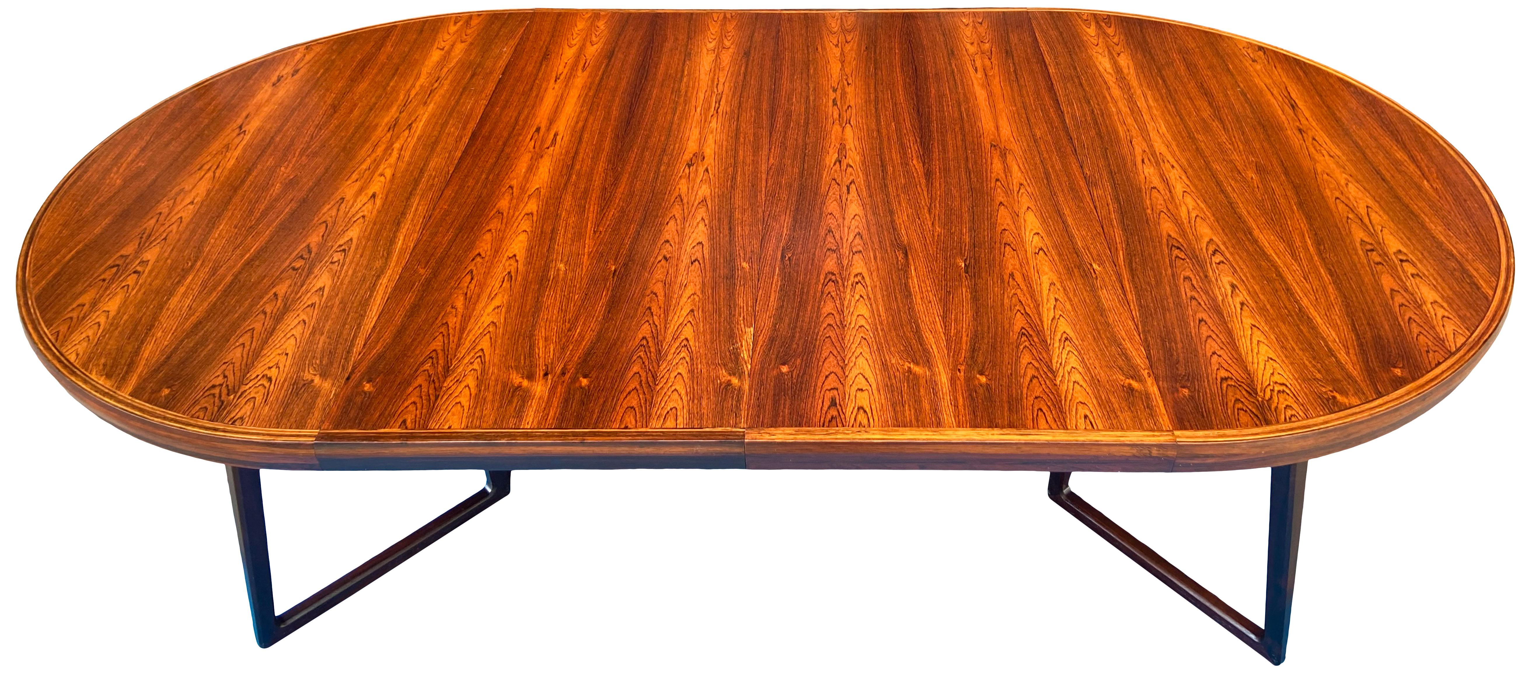 Rare Danish Modern rosewood gate leg dining table with two leaves. This beautiful table is round / circular when closed and elliptical when extended. A wonderful example of Brazilian rosewood showing highly figurative details. The legs are solid