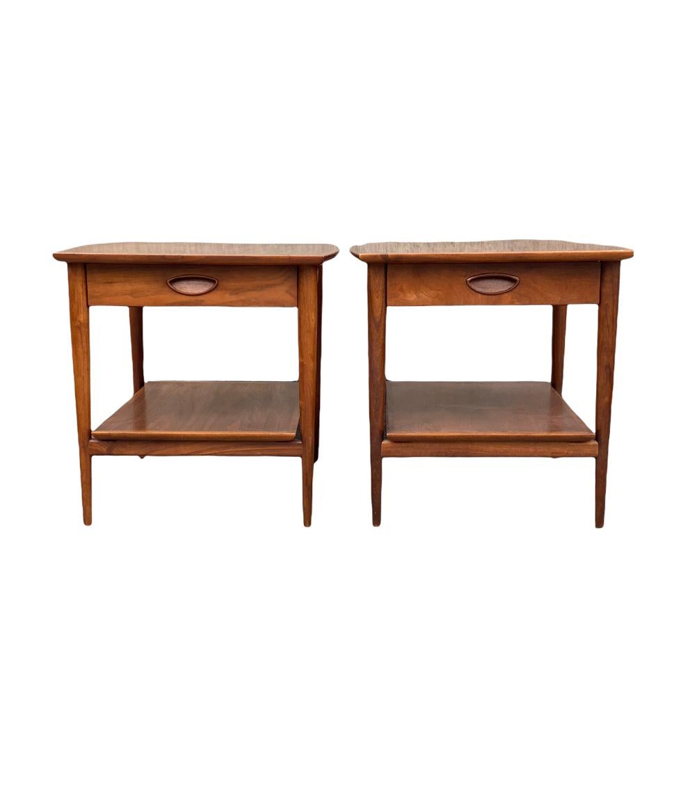 Elegant pair of matching nightstands with handsome lines and beautiful walnut tones. Beautifully figured grain pattern adorn this pair, elegantly executed in American walnut. Manufactured by Henredon from the Heritage line. Sculptural wood pulls,