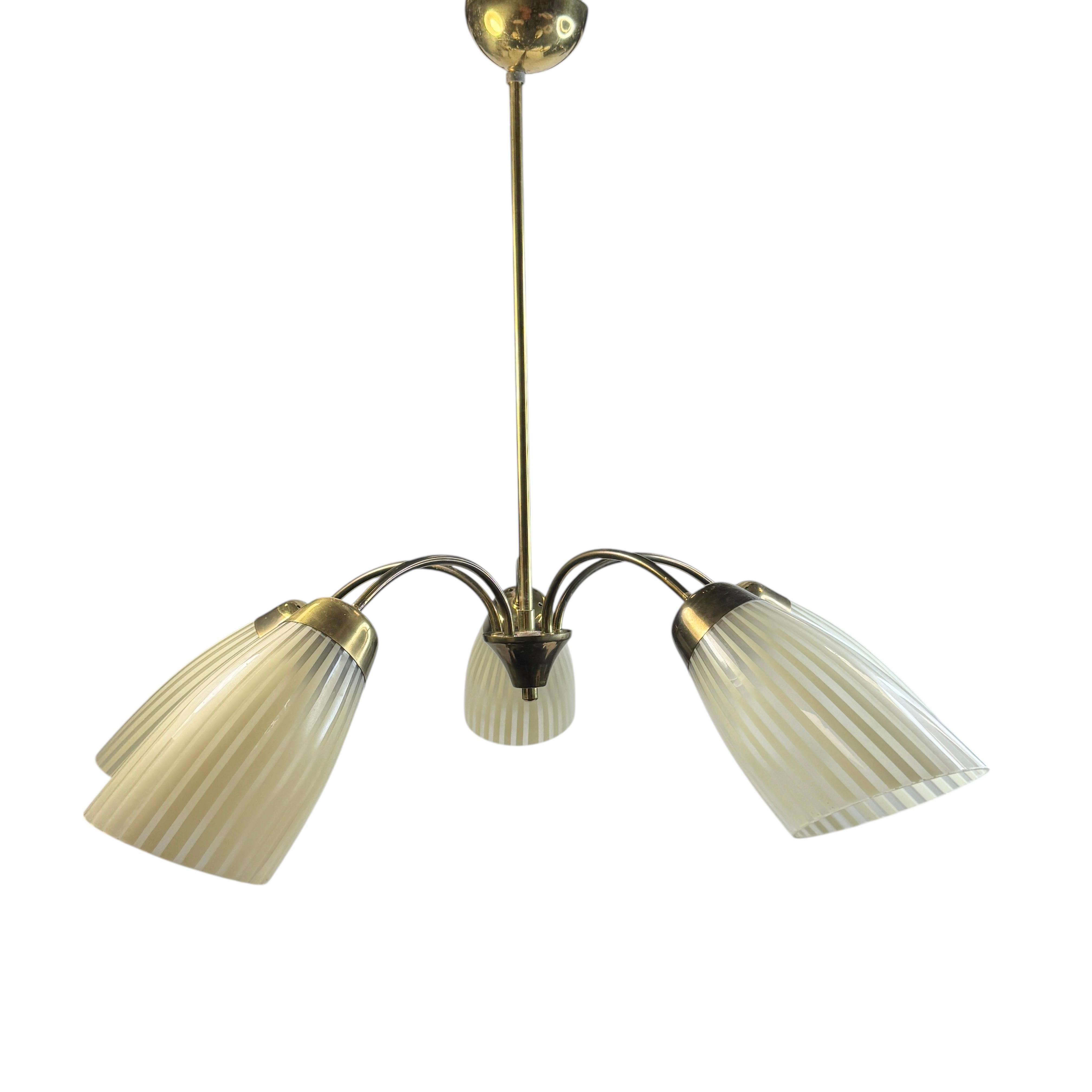 Bellissimo e decorativo lampadario in ottone, dotato di cinque prese E27 con paralumi a forma di cono in vetro acidato a righe. Prodotto in Germania negli anni '50. L'apparecchio richiede cinque lampadine europee E27 / 110 Volt Edison, ciascuna con