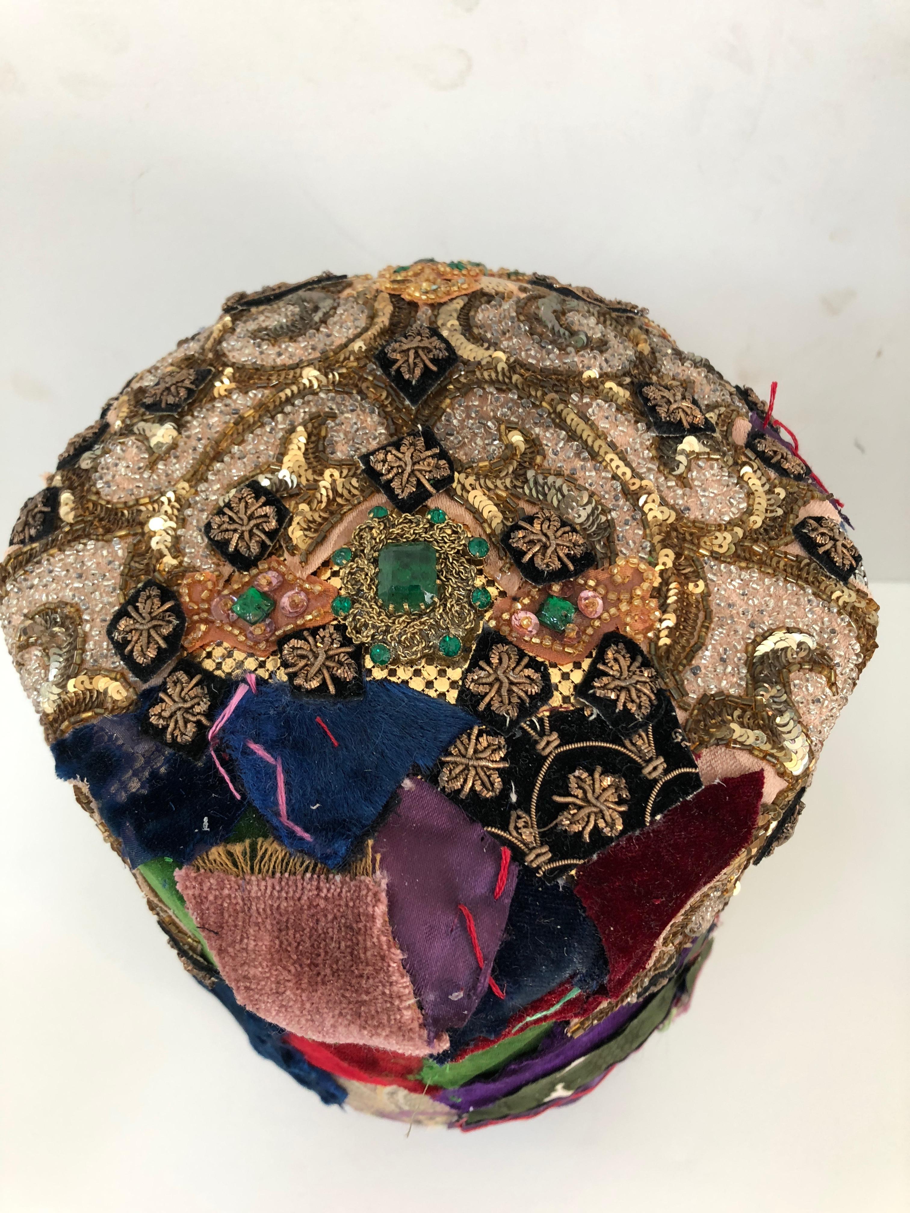 Beautifully handmade found object sculpture that originated as a vintage wood rotating hat form, and has been transformed into a sumptuous work of art. The head and base is meticulously collaged with pieces from a velvet crazy quilt, silver and gold