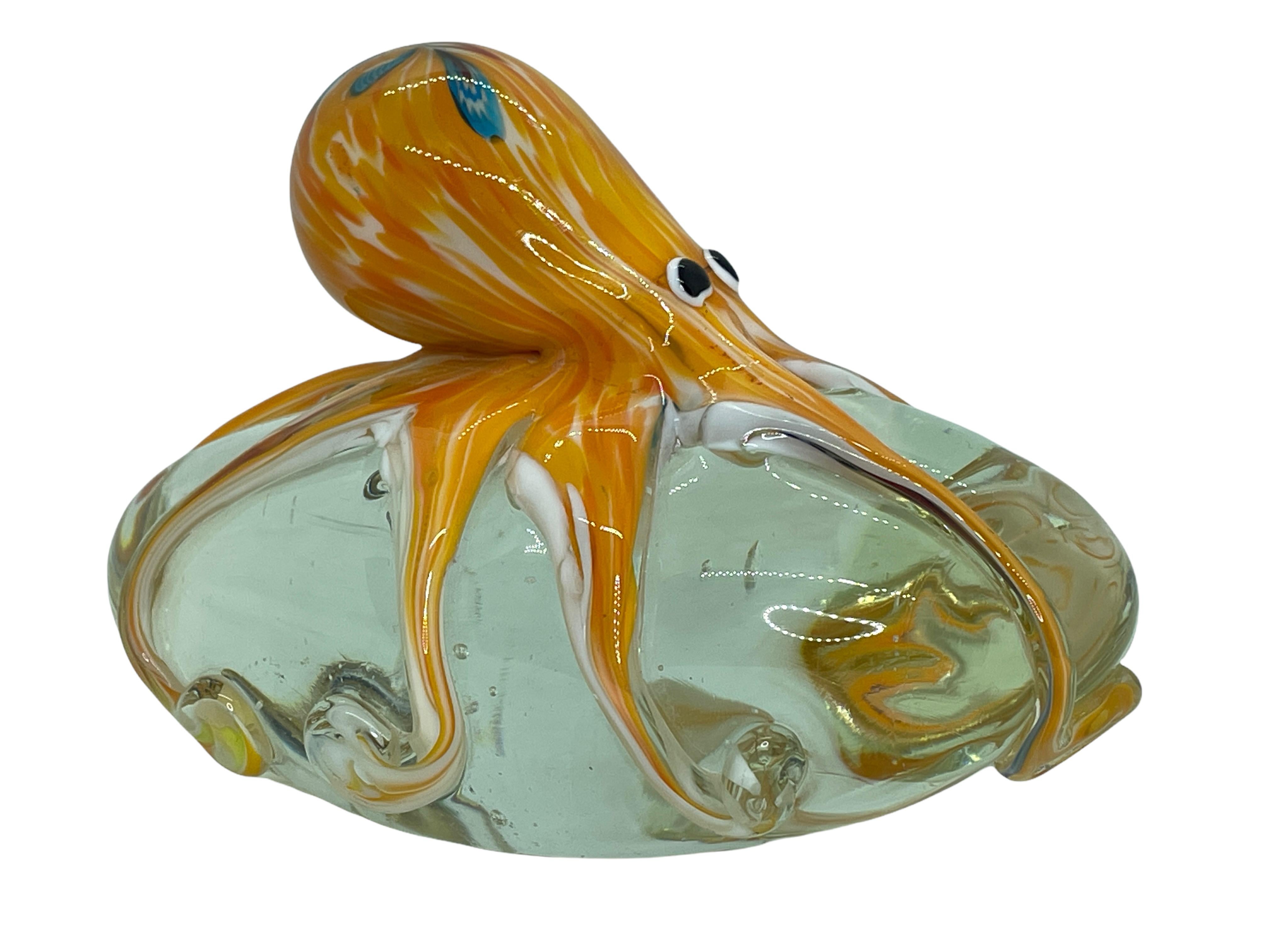 Beautiful Murano hand blown aquarium Italian art glass paper weight. Showing a giant octopuses, on a glass stone. Colors are a red, grey, white, black and clear. A beautiful nice addition to your desktop or as a decorative piece in every room.