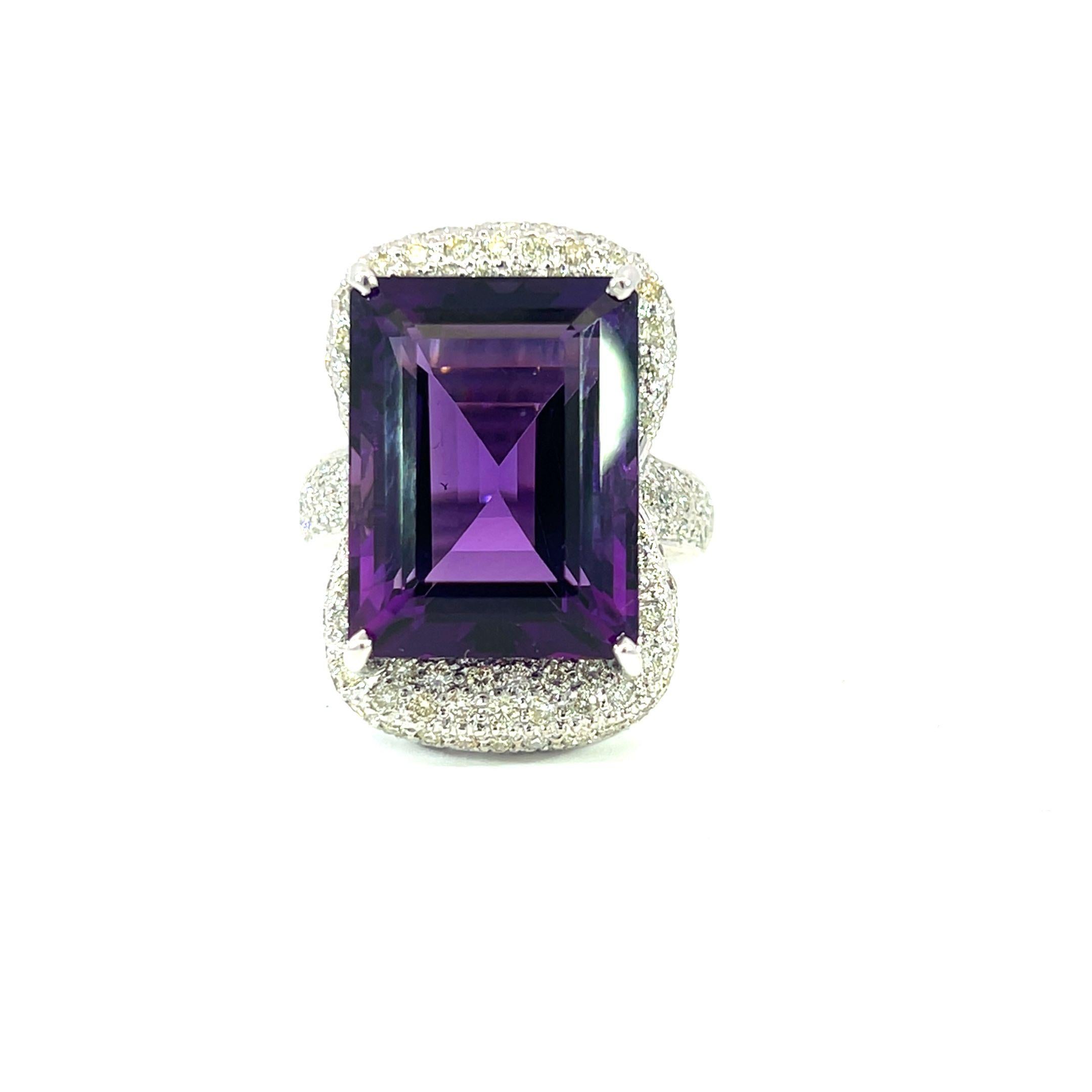 Una magnífica y enorme gema amatista de 20,87 quilates está engastada en una brillante banda de 18 quilates con incrustaciones de diamantes de 1,54 quilates en este precioso anillo. Los deslumbrantes diamantes contrastan con el intenso tono púrpura