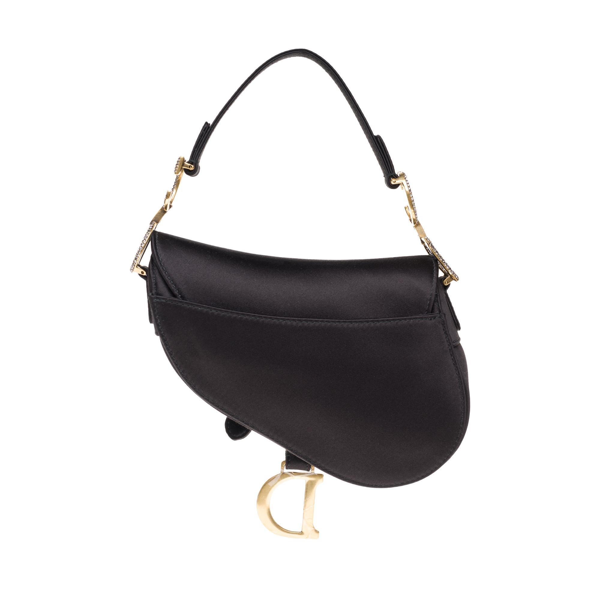 Gorgeous Bag Dior Saddle in black satin, trim in gold-tone metal with rhinestones, simple satin handle allowing a hand or shoulder stand.

Zip closure.
Black satin inner lining.
Signature: 