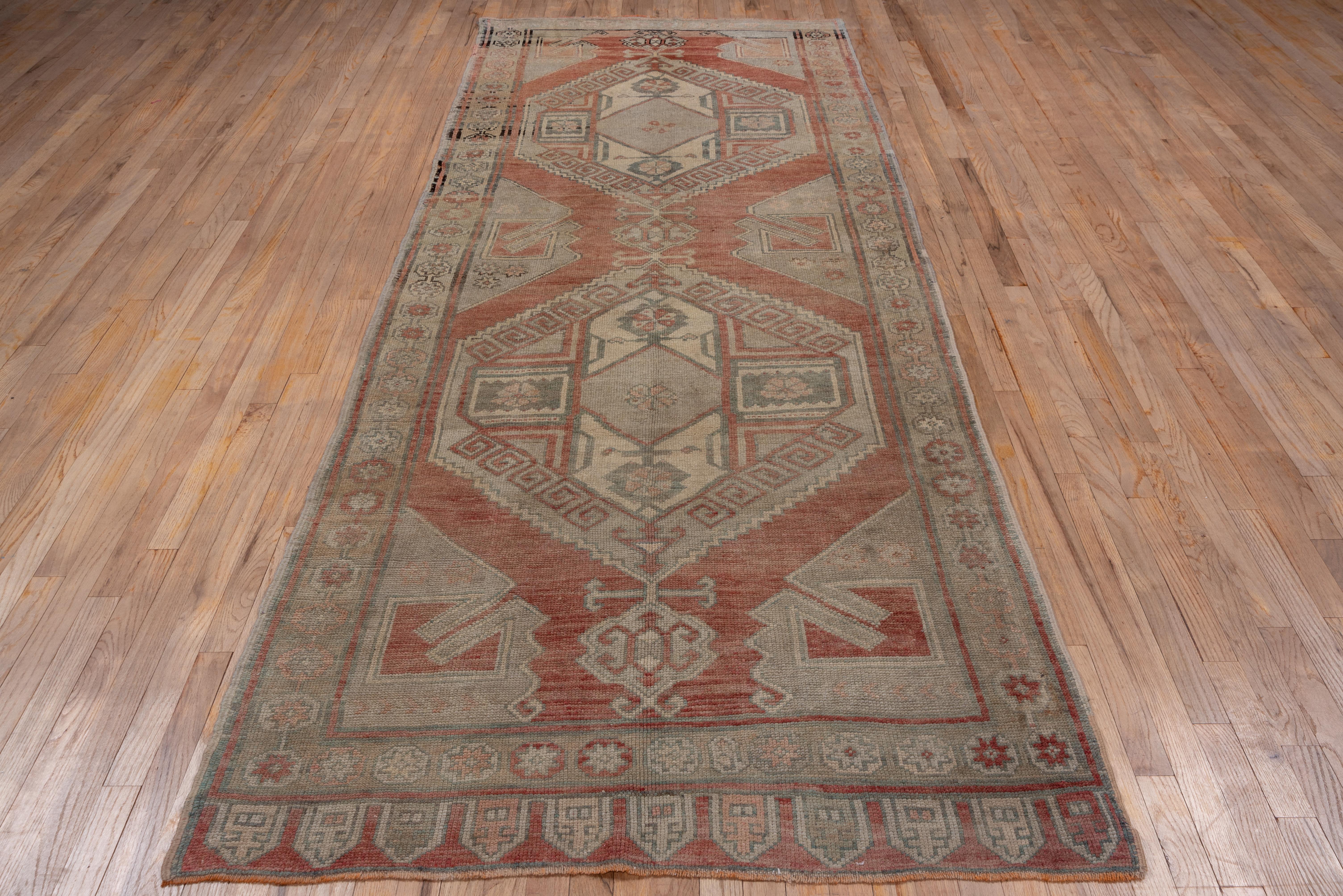 From the Karapinar subgroup, this salmon ground short gallery carpet shows two characteristic connected, stepped and hooked hexagonal medallions with cruciform centres and simple, pinched pendants, all in soft tones of buff, cream, pearl and