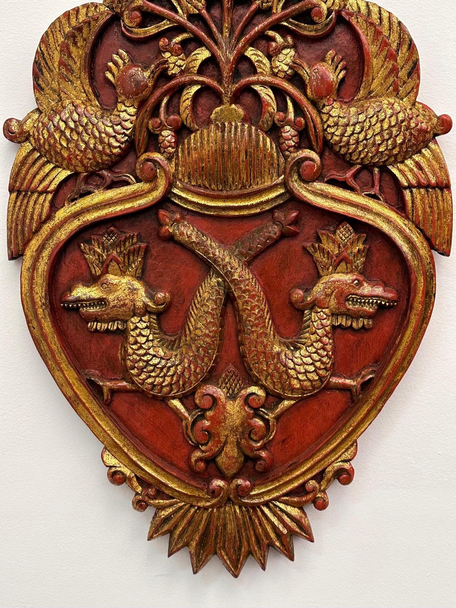 Remarquable paire de plaques murales en forme de bouclier, sculptées à la main, avec une sous-peinture rouge et une dorure, et une décoration ornée.